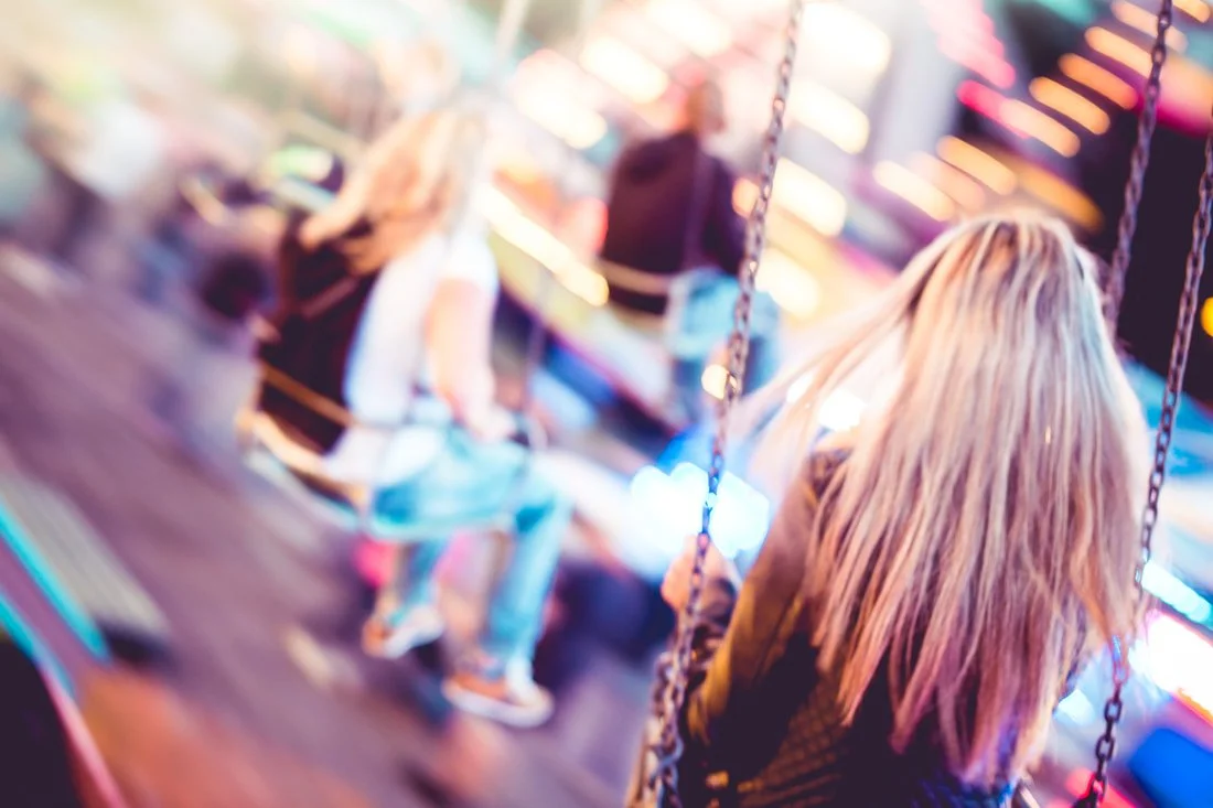 Image of woman from the back riding on a carousel swing