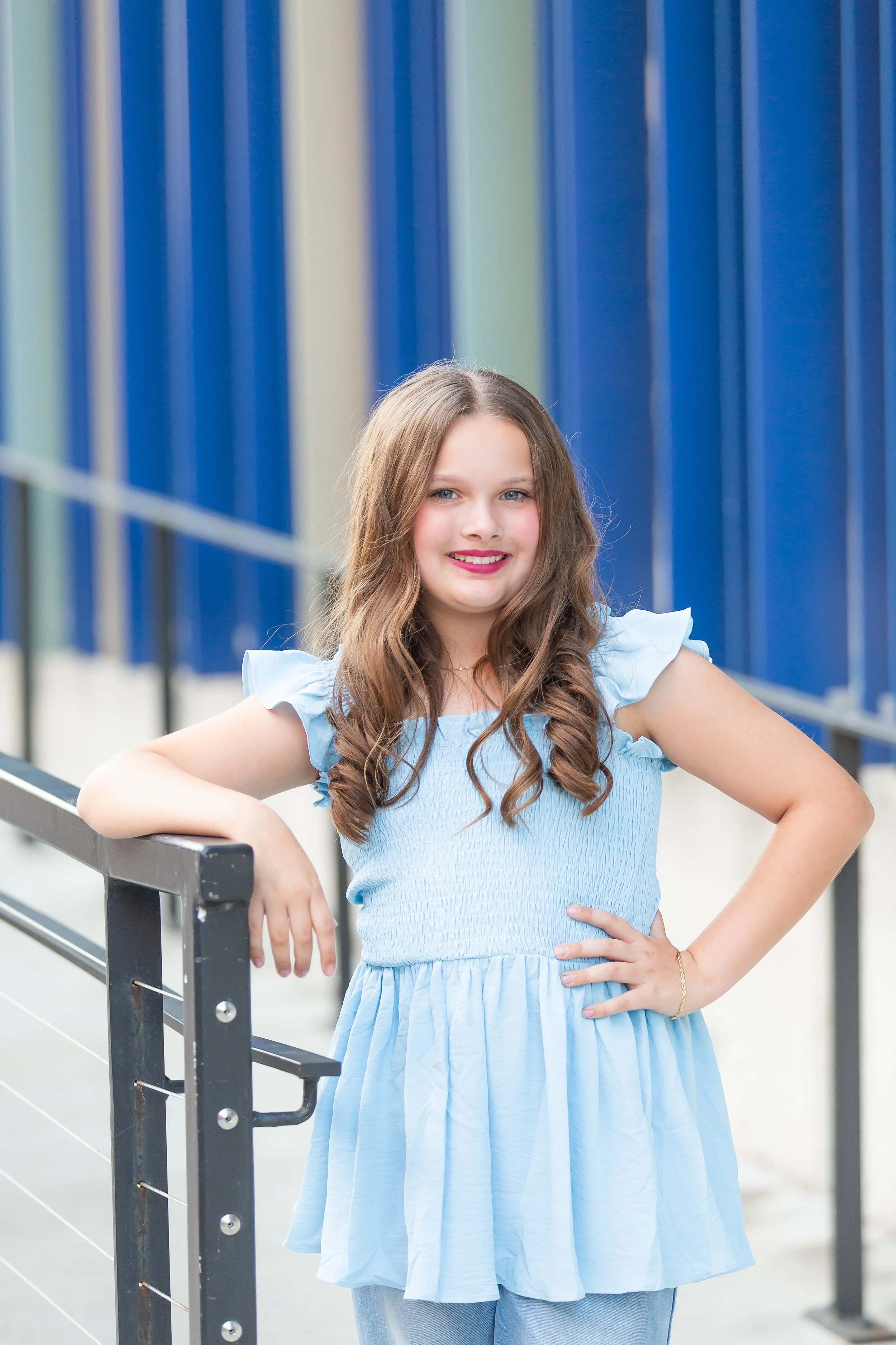 Young girl in blue dress posing on stairs