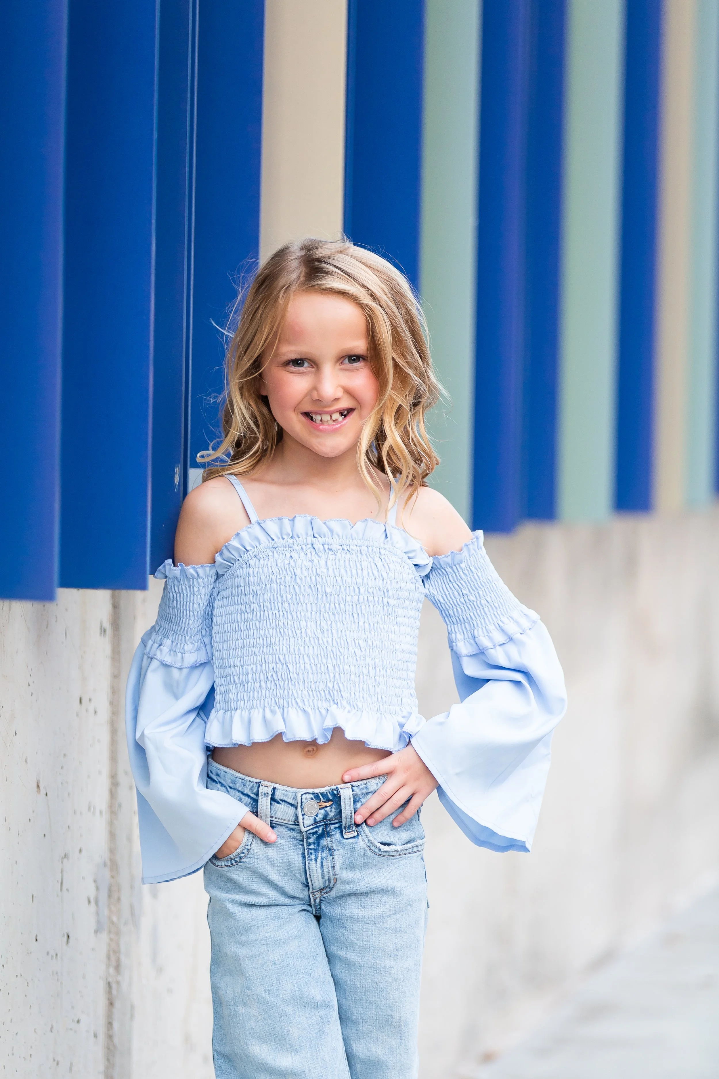Young girl in blue dress standing on stairs.