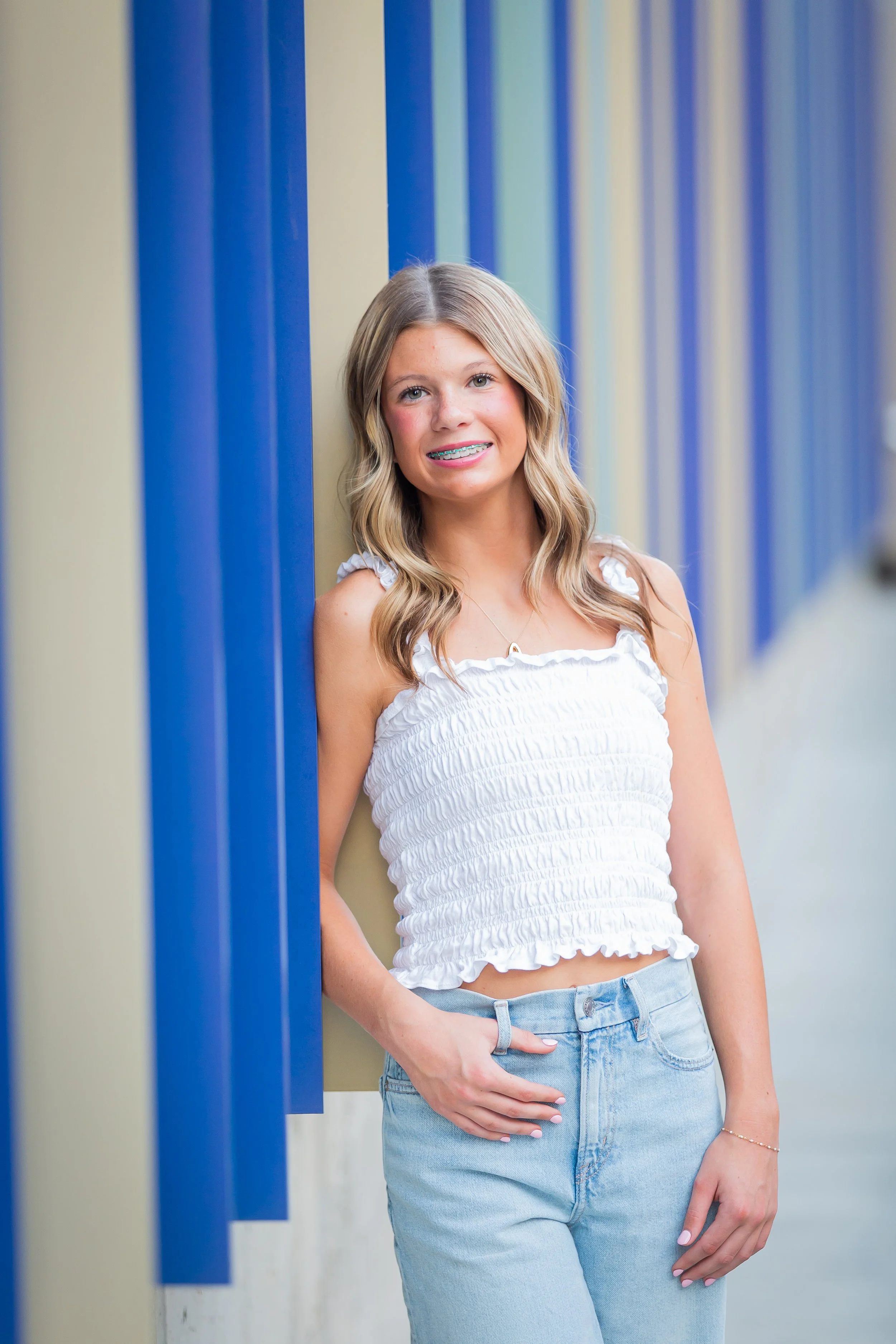 Person with long brown hair in blue dress standing by railing on staircase.