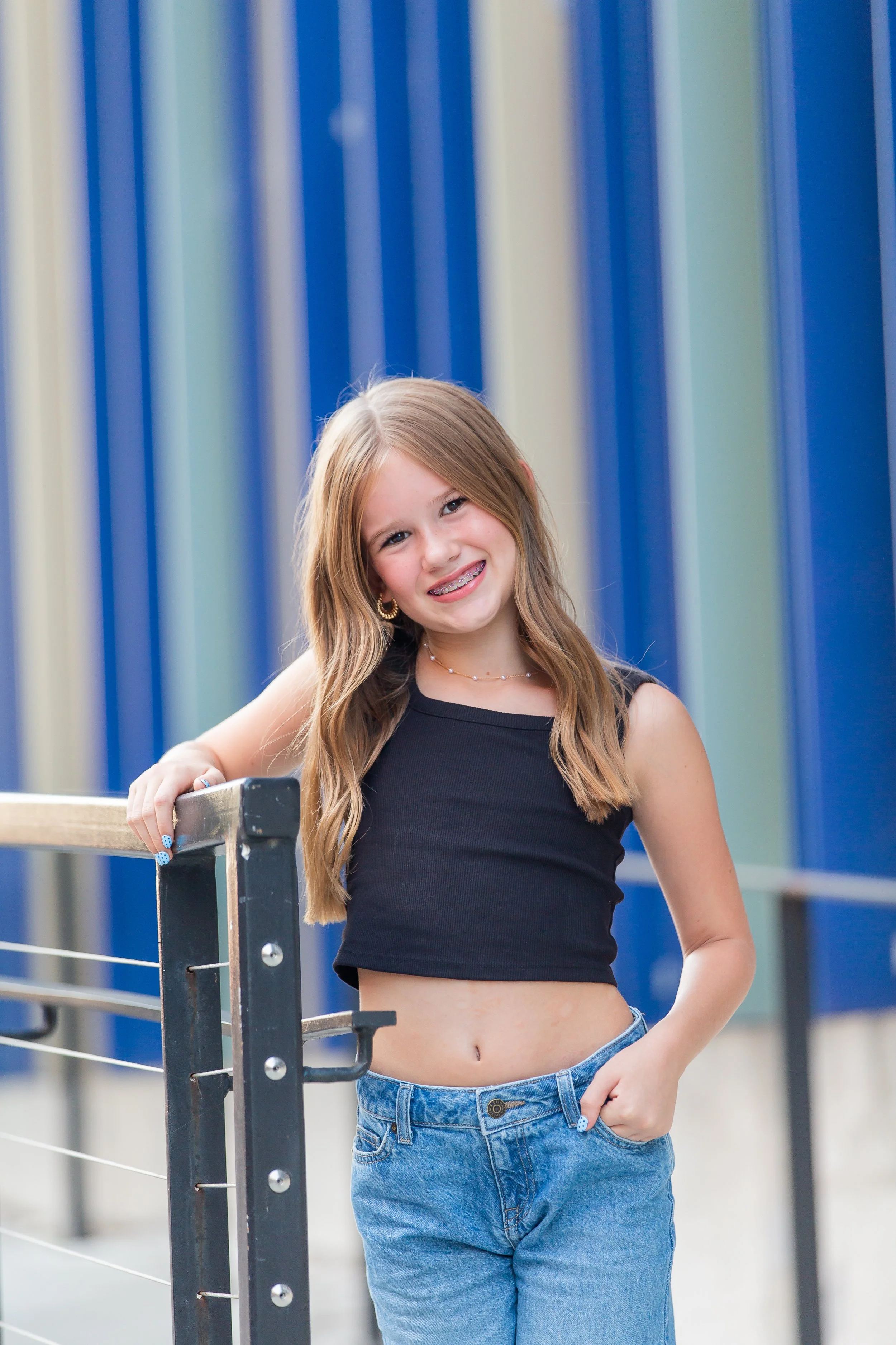 Girl in blue dress sitting on steps, smiling.