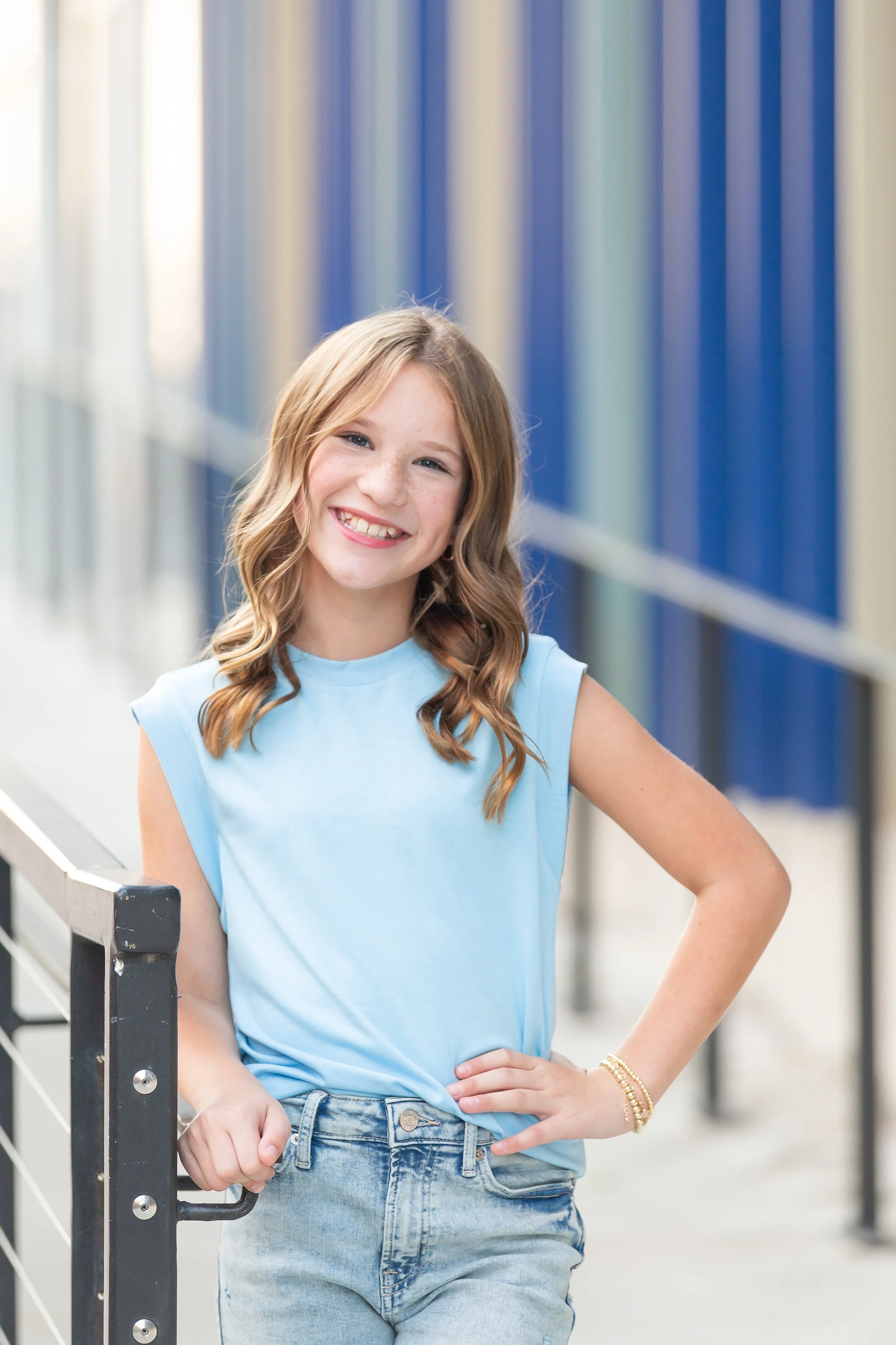 Young girl in a blue dress standing on metal stairs