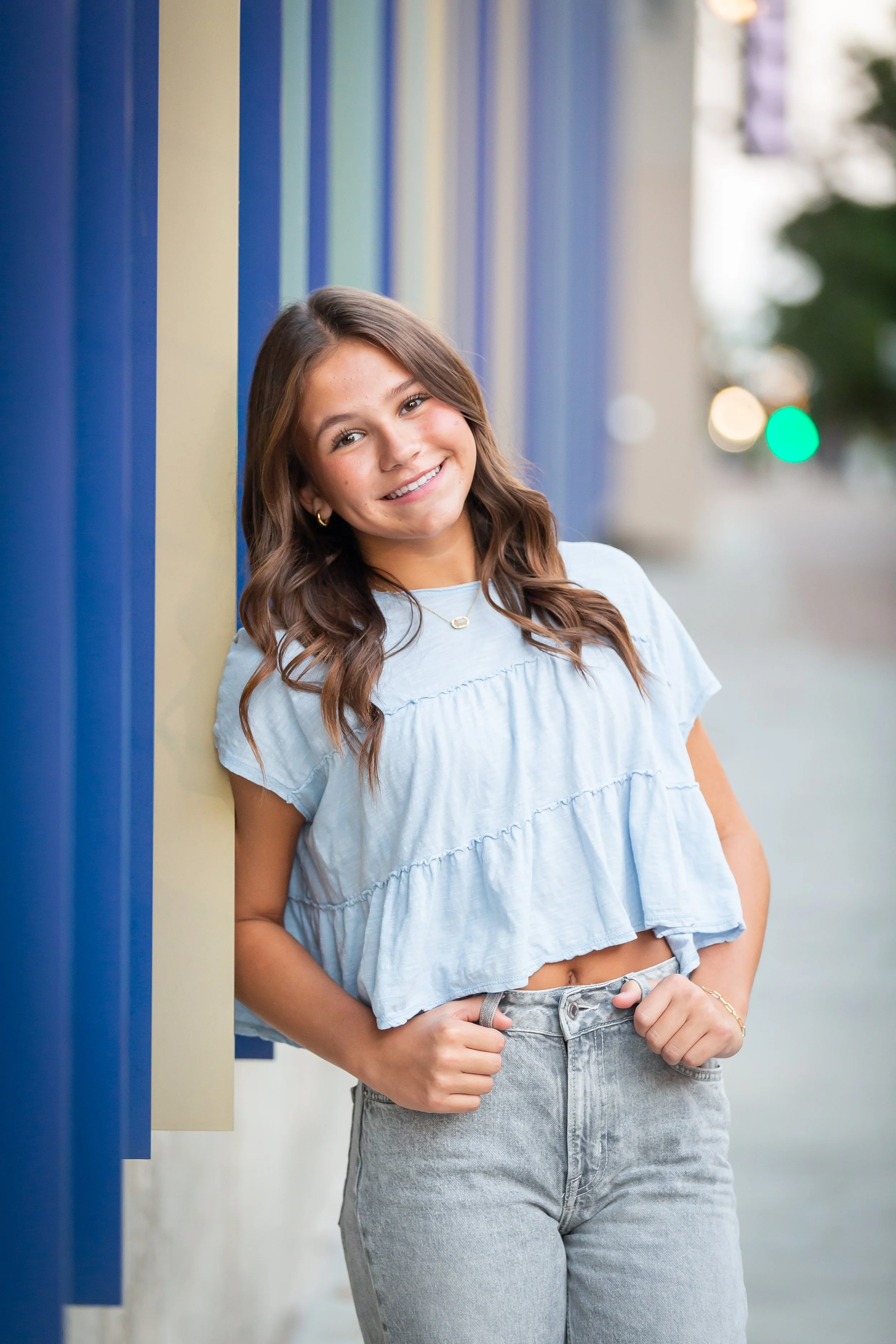 Smiling girl in blue dress leaning on outdoor metal railing