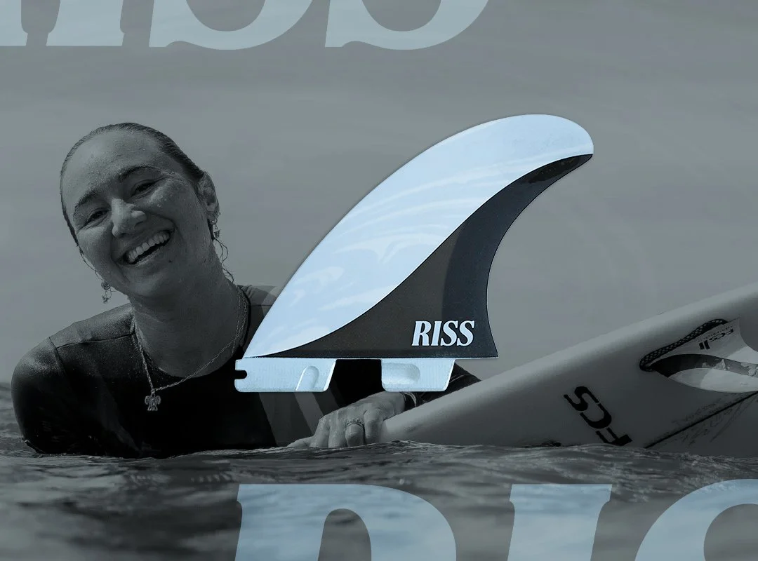 A city building with a large advertisement for Carissa Moore, featuring a black and white photo of her holding a surfboard on the left, and a color photo of her surfing on the right, with the text 'FCS' and her name.