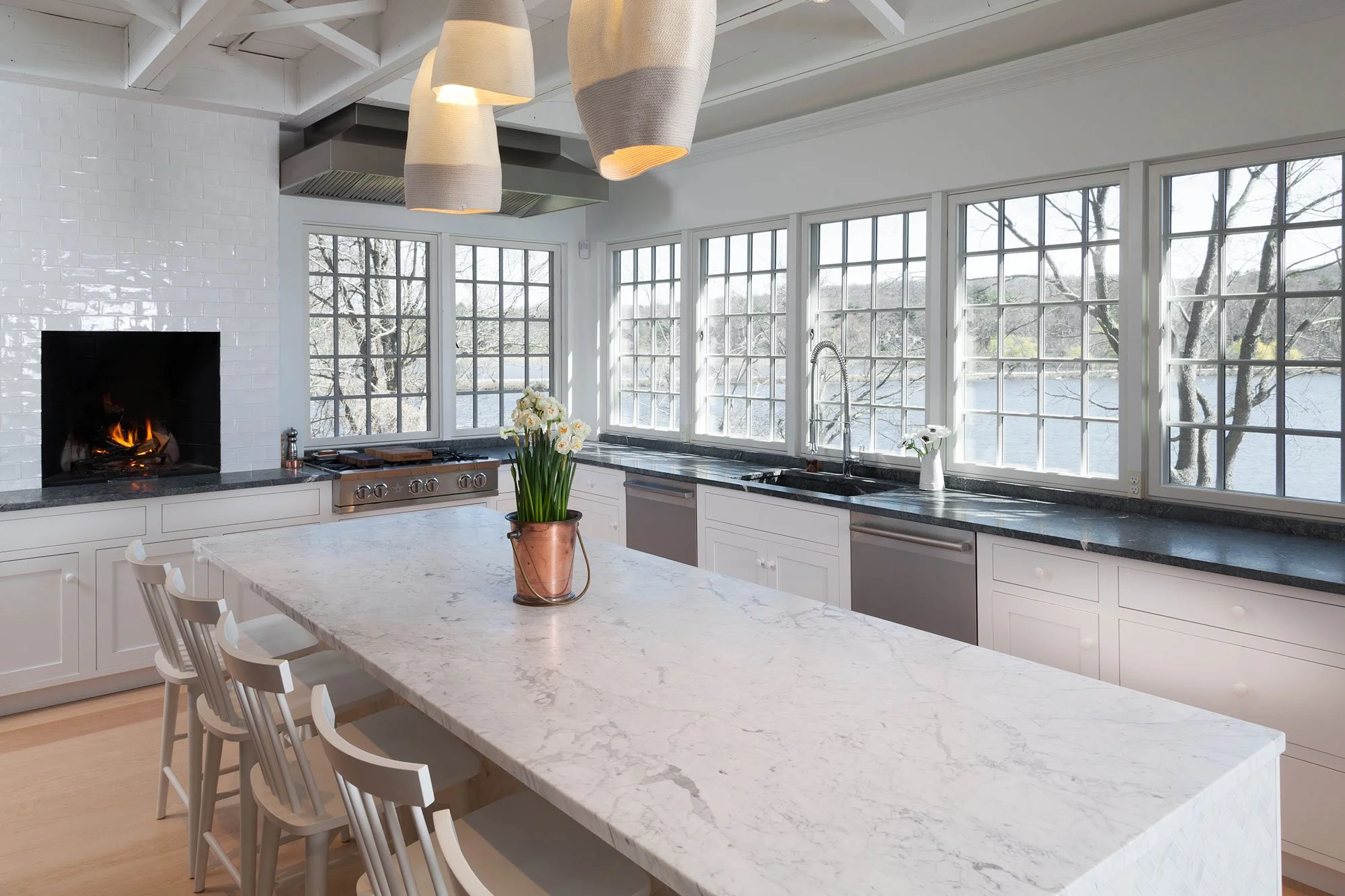 Crystal Cabinets - Black and white inset shaker kitchen. No upper cabinets. Lake house kitchen. Fireplace in kitchen. White kitchen with subway tile. Large island.