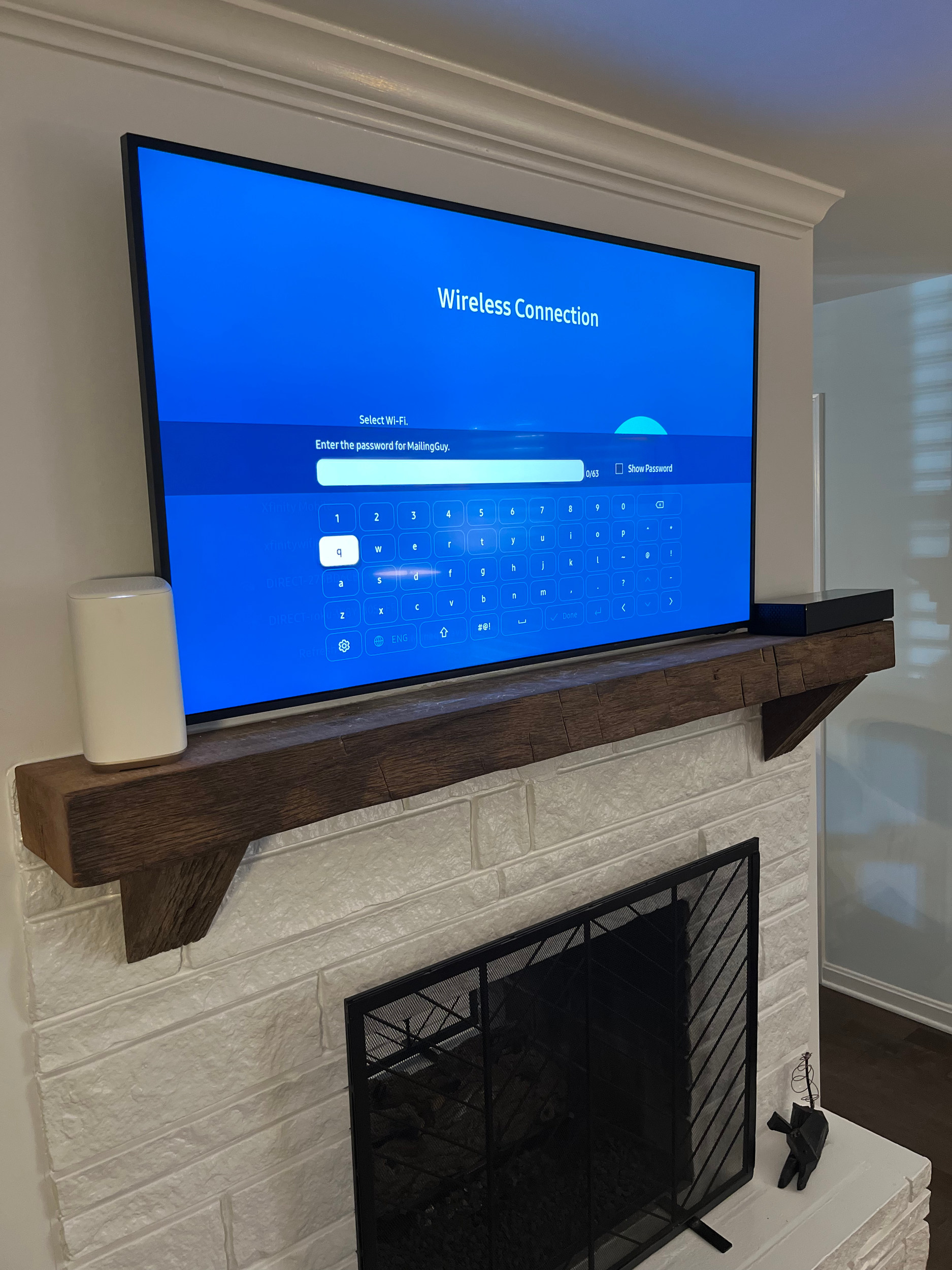 Flat-screen television displaying a wireless connection setup screen, placed on a wooden stand in front of a white brick fireplace.