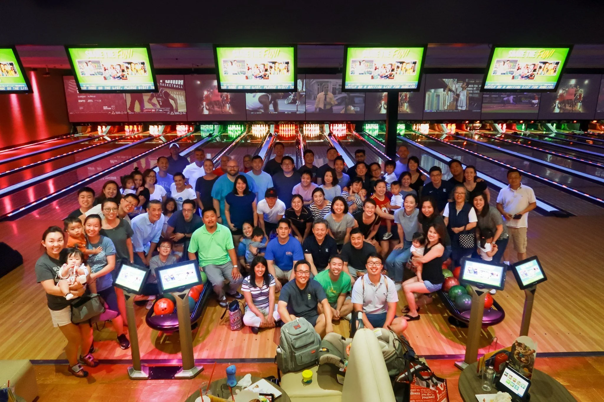 A group of about 80 Forest Church members pose together for a picture at a bowling alley.