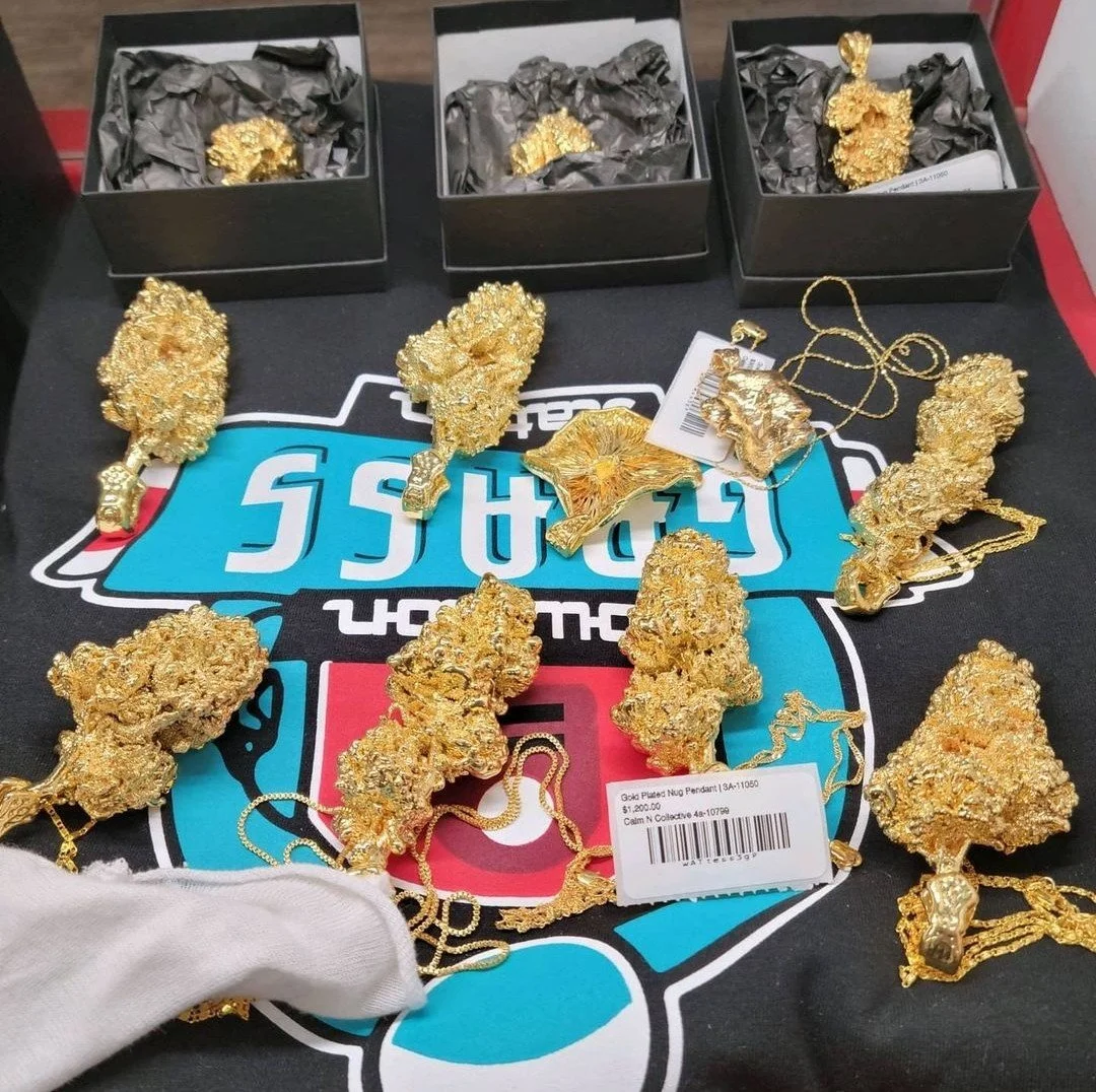 pot bud dipped in solid gold, on gold chain necklace on display on a Houston Grass Station t-shirt