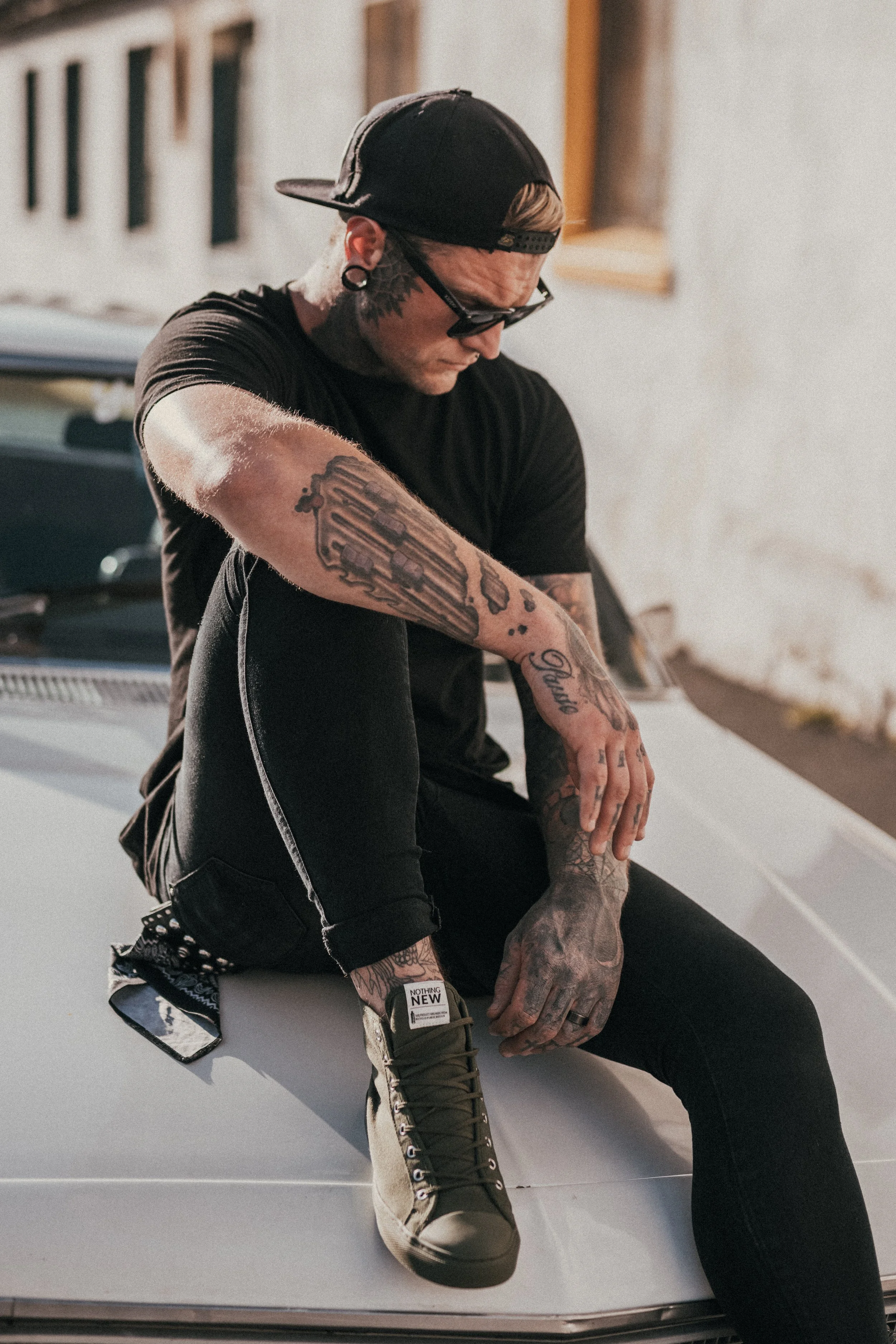 Fashion photography for Nothing New Footwear of a tattooed model sitting on a muscle car in Cape Town, South Africa by photographer Vanartist