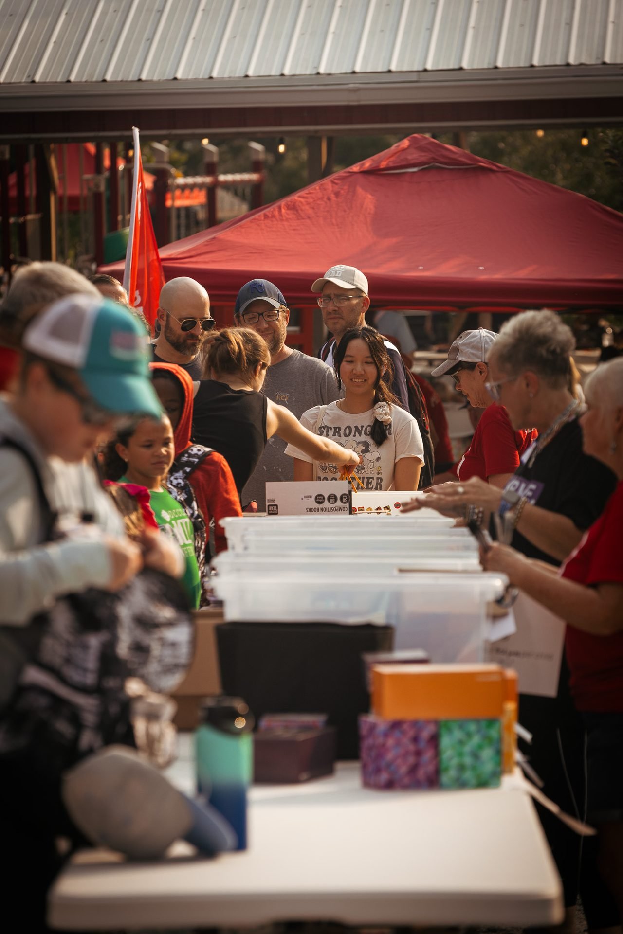 Families select free school supplies from bins as volunteers help at a Joy Meadows back-to-school event.