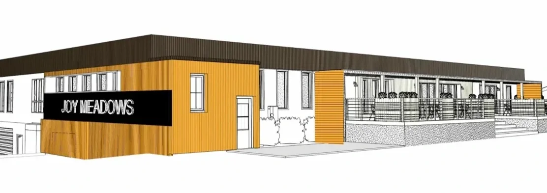 Architectural rendering of Joy Meadows, a foster care community model in Kansas, with a porch, railings, and outdoor seating.