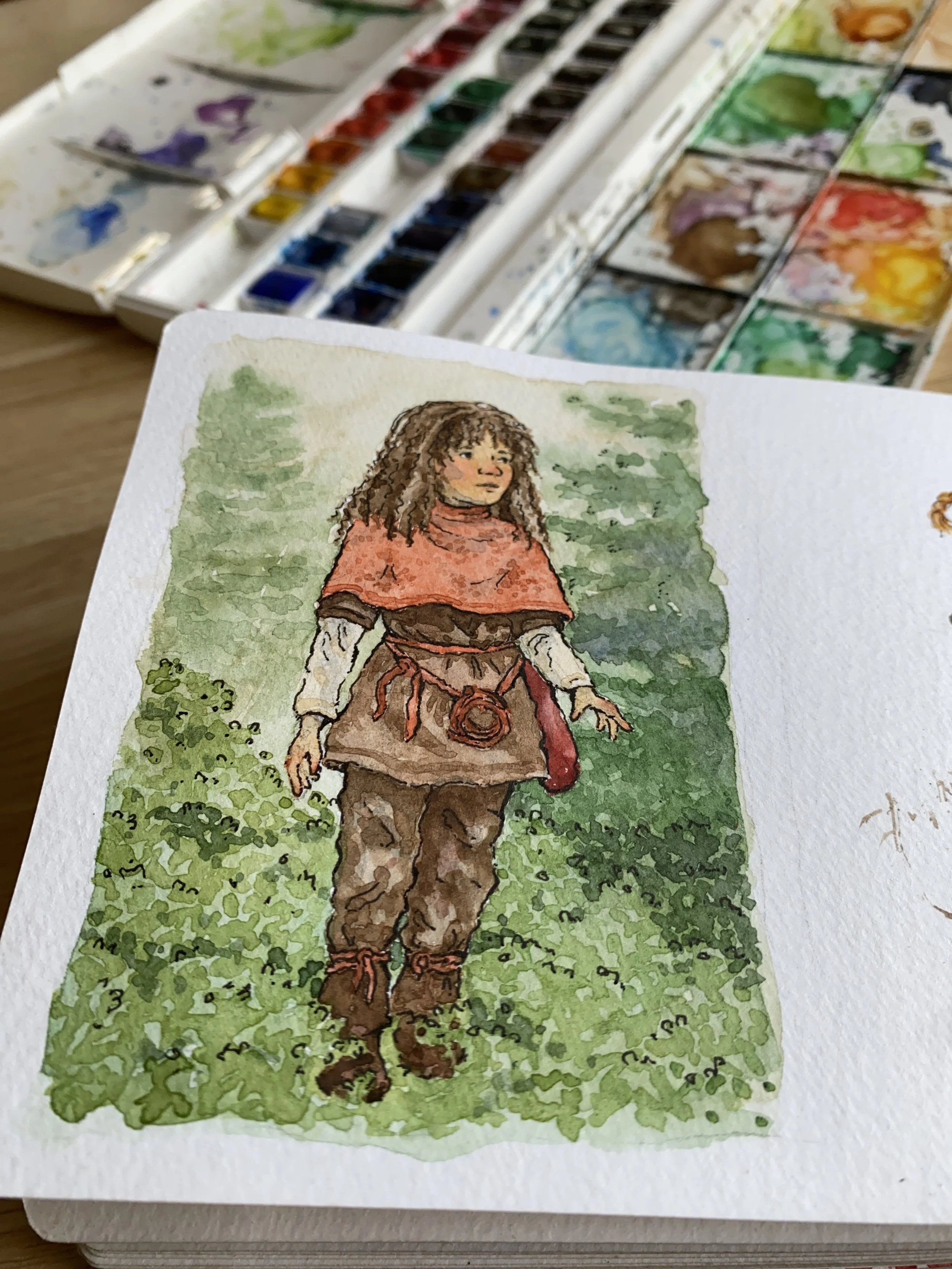Watercolor illustration of a girl with curly hair walking outdoors on grass, wearing a brown outfit with a red cape and a small red pouch.