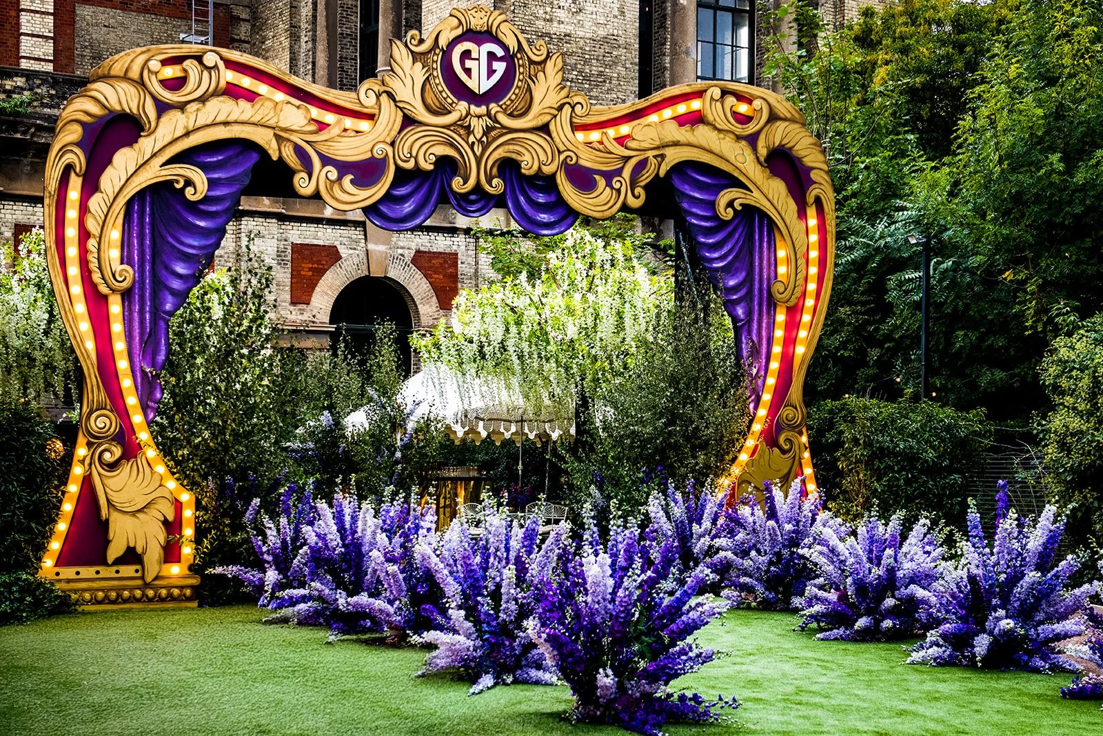 Bespoke scenic entrance, faux grass walkways and vivid planting for a private celebration at Alexandra Palace Theatre produced by Blu Fire Ltd.