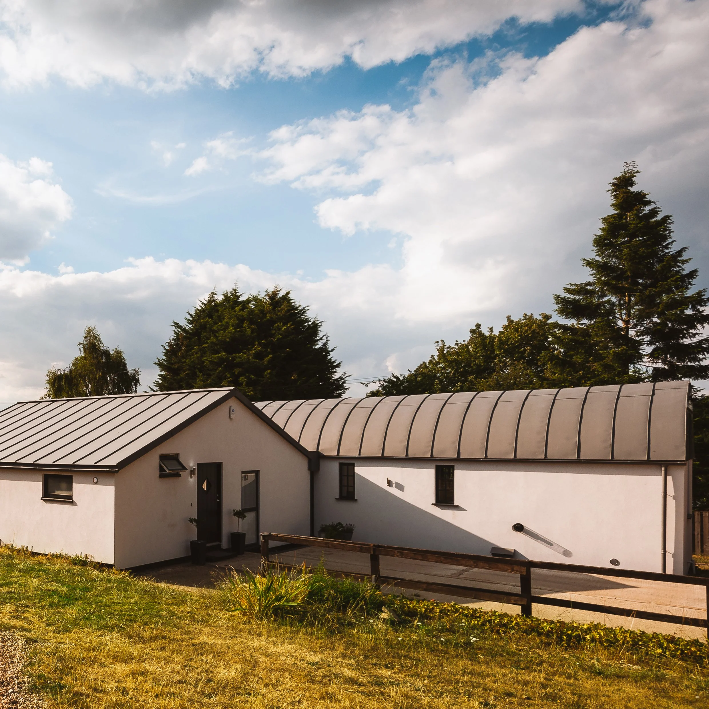 Exterior Façade of New Barn conversion to Existing Dutch Barn connected with a modest glazed link to the adjacent storage building.