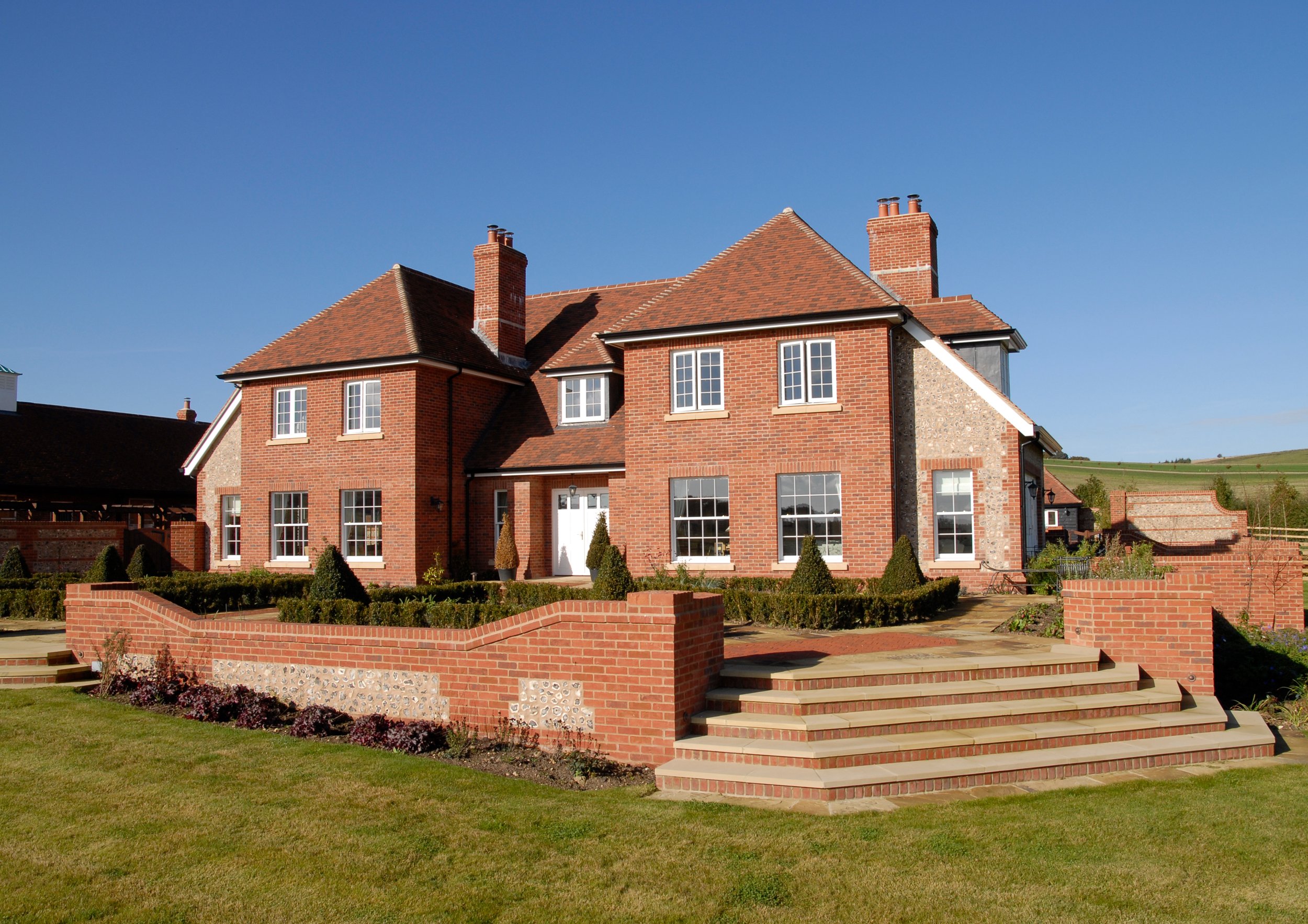 New Substantial home build to embrace the familiar traditional farm layout and style, build within new equestrian estate development in Wiltshire, seen from rear elevation with vast countryside in the background.