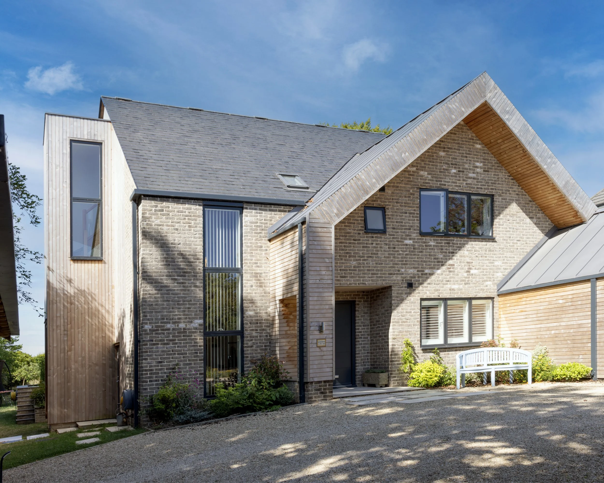 Rear elevation of new light-filled contemporary home with accompanying outside patio seating area which benefits from the views onto generously sized garden.