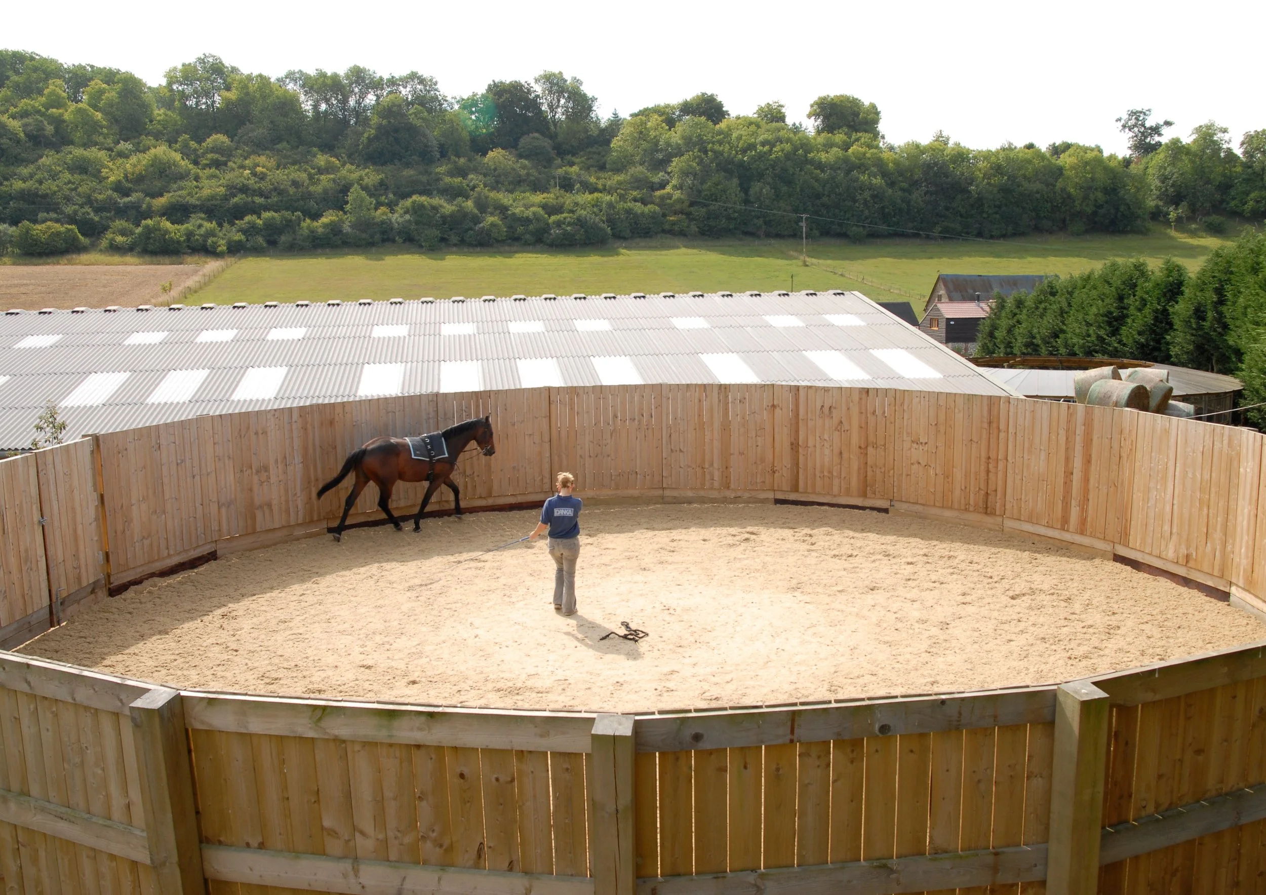 arena within new equestrian site development with horse and trainer in the centre