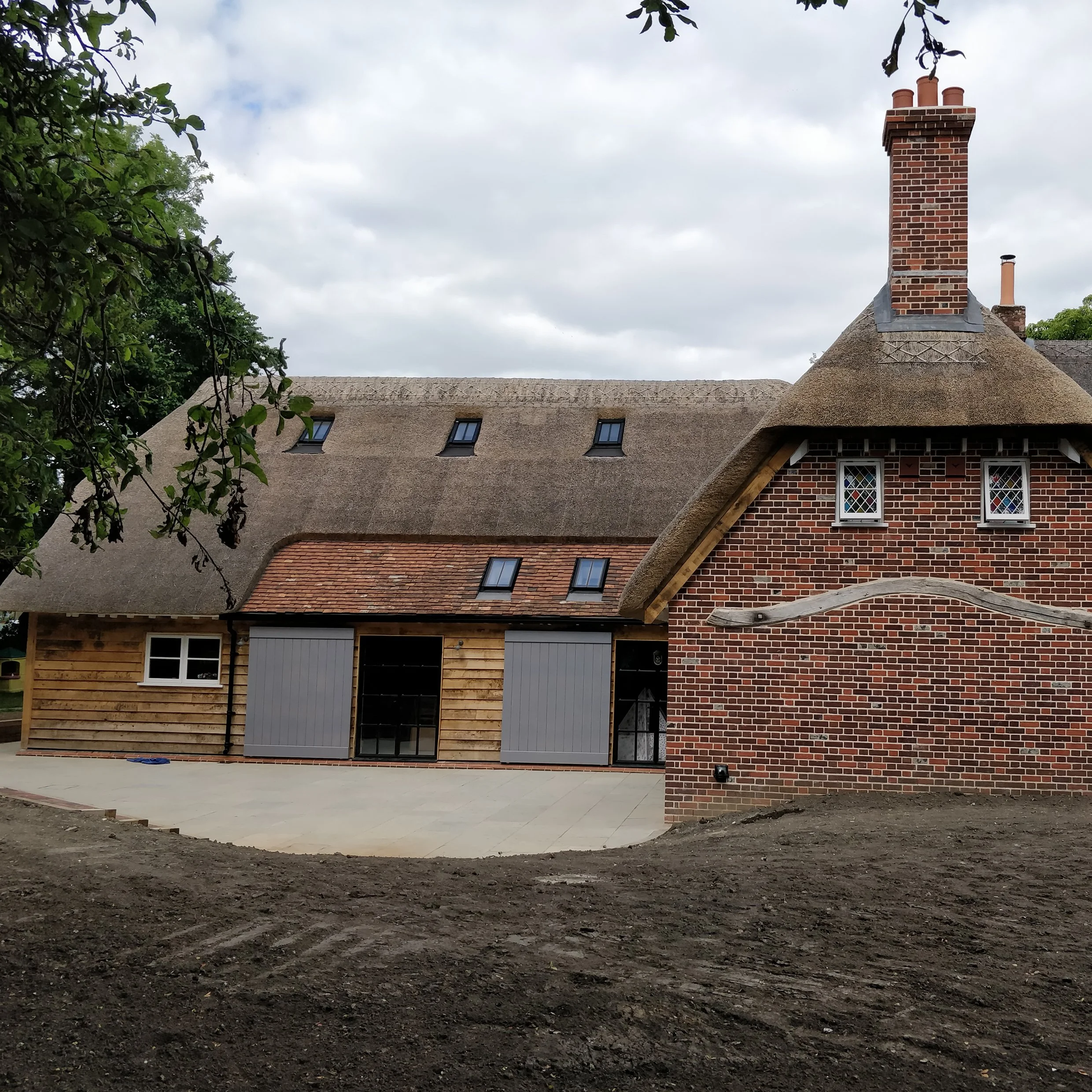 Elevation of new oak framed timber barn extension to a listed cottage with thatched roof