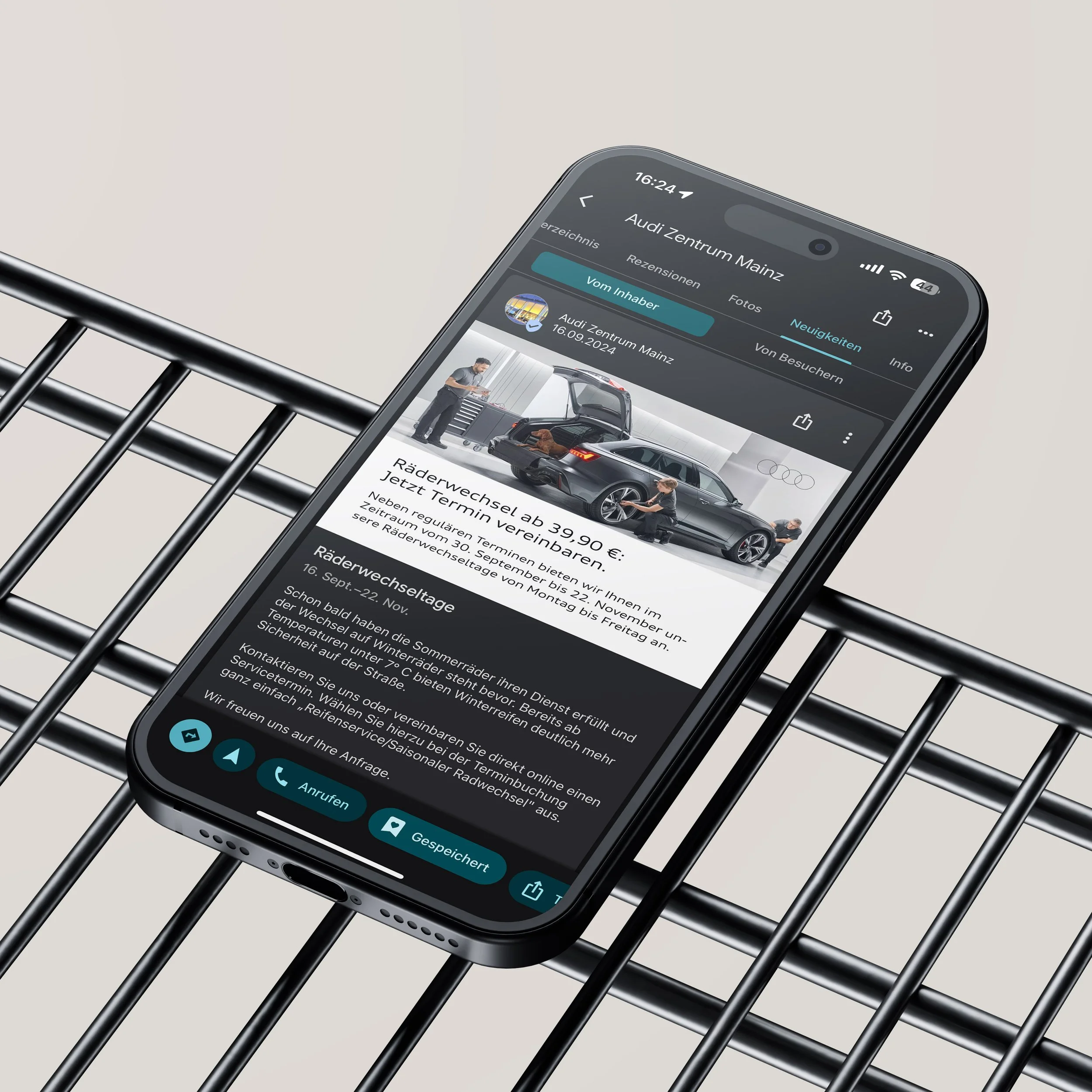 Smartphone zeigt eine Webseite vom Audi Zentrum Mainz, die einen Termin für einen Radwechsel ab 39,90 € anbietet, mit Bild eines Autos und Werkstattpersonal.