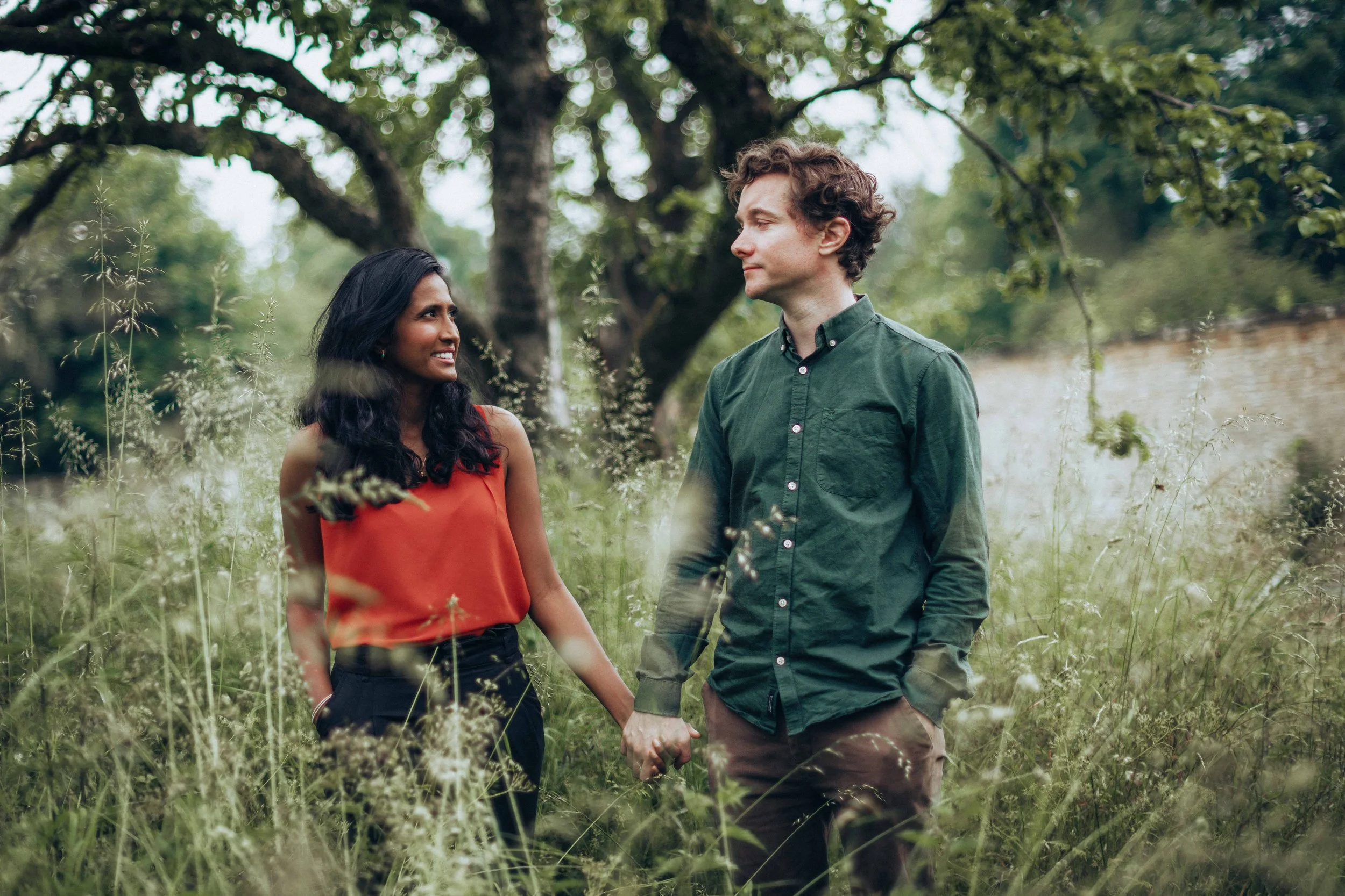couple holding hands in lush meadows for engagement session near Cambridge