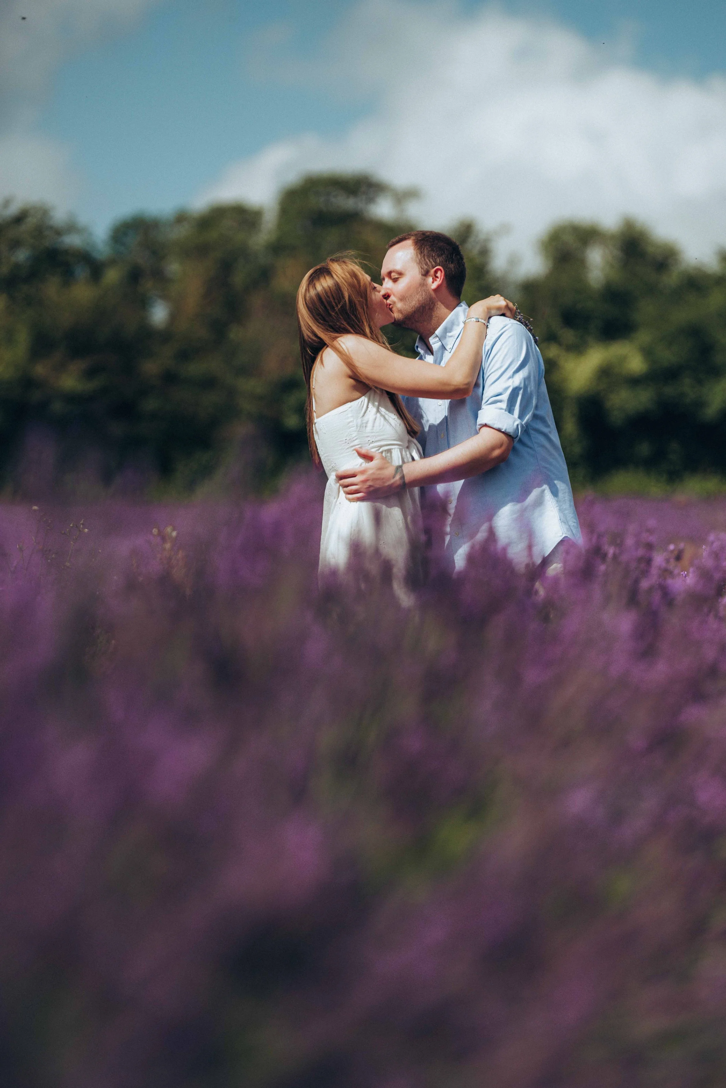 A couple sharing a kiss while standing in a lavender field at Castle Farm in Kent