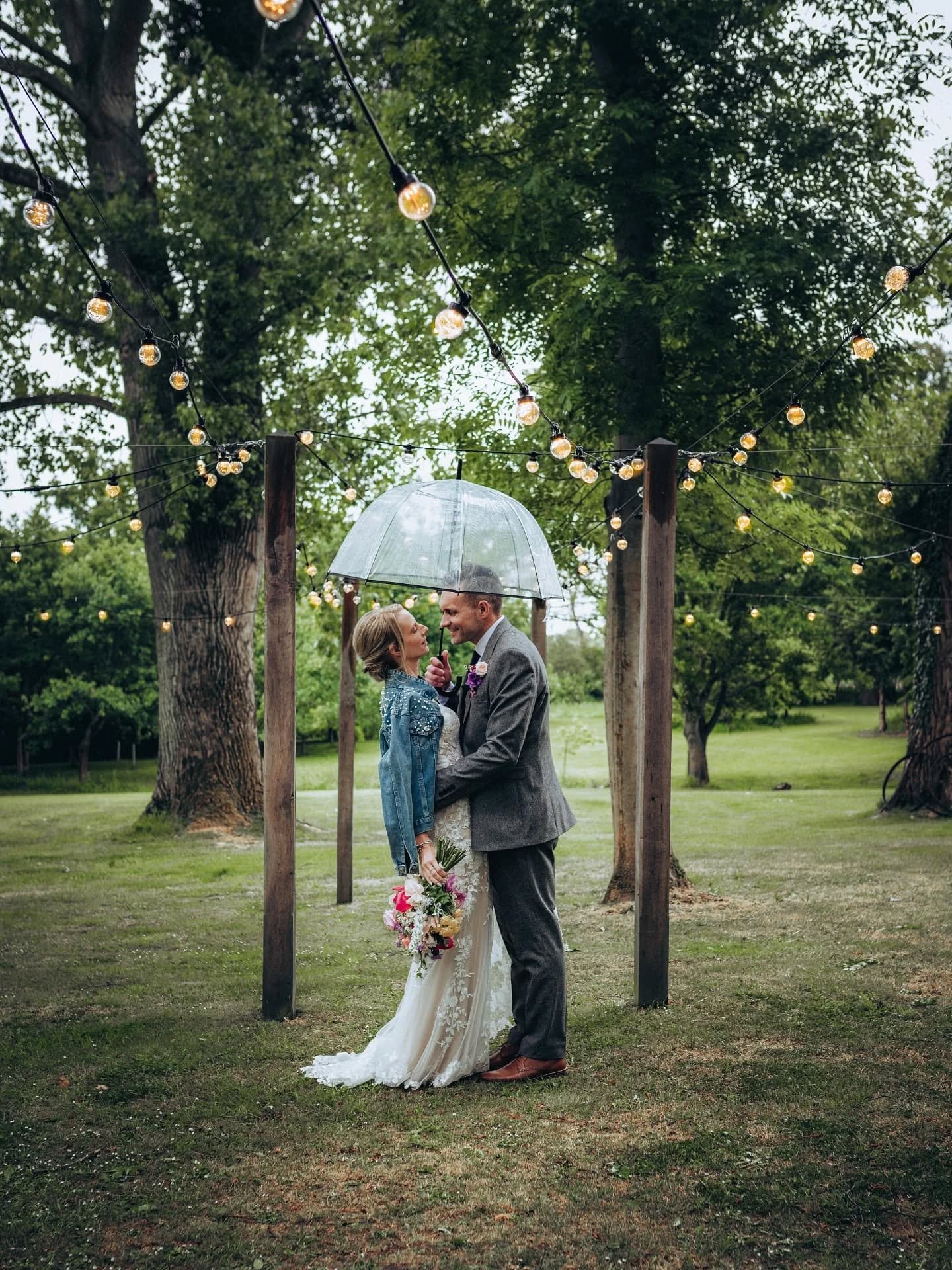 Rainfall, glowing fairy lights, and the cosiest barn celebration. Natalie and Carl on their wedding day, all smiles beneath their umbrella in the beautiful gardens of The Tudor Barn, Belstead.

Venue @thetudorbarn
Wedding coordinator @louisamayweddin