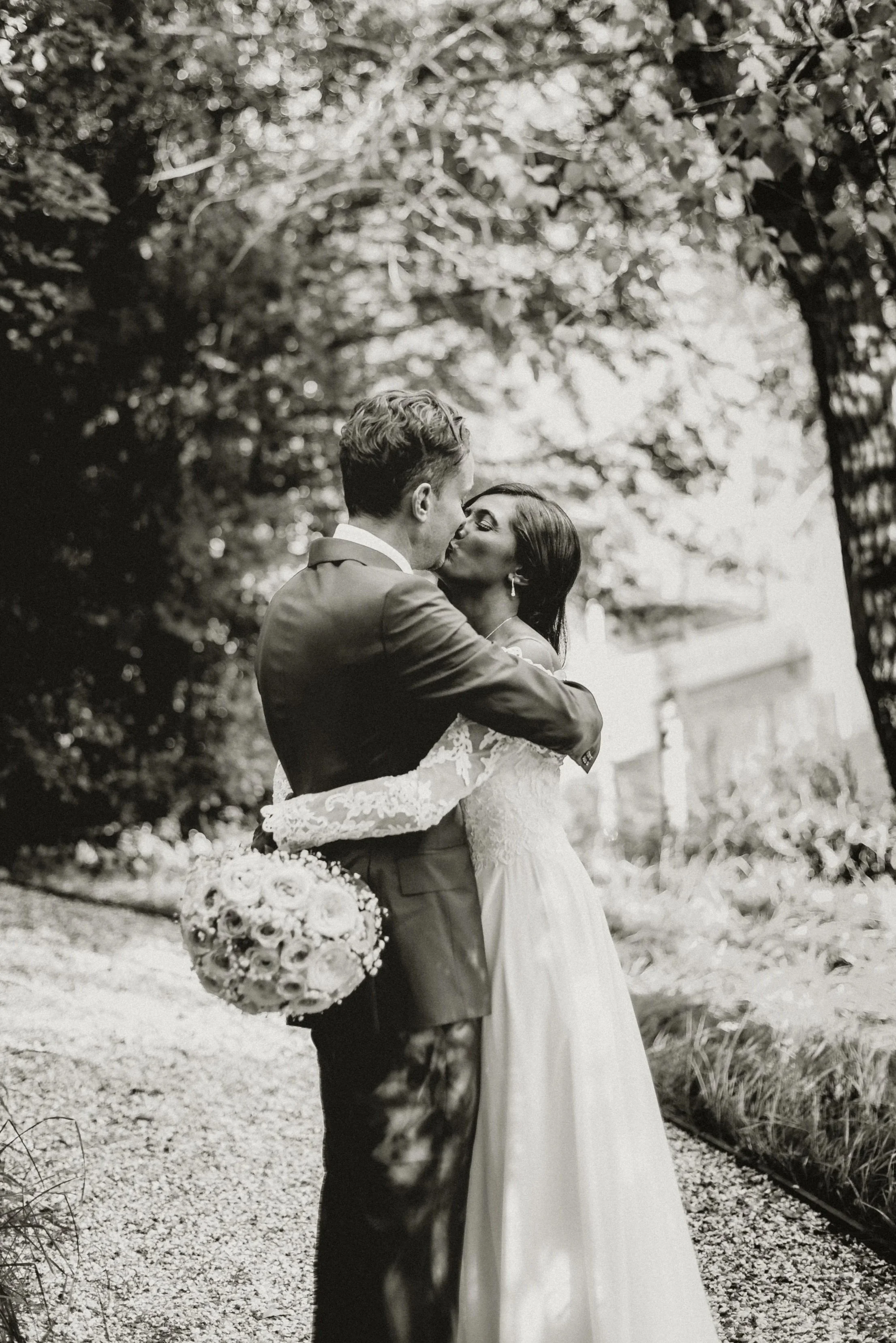 Bride and groom embracing each other and share a kiss in a wooded area at East Mersea Hall near Colchester