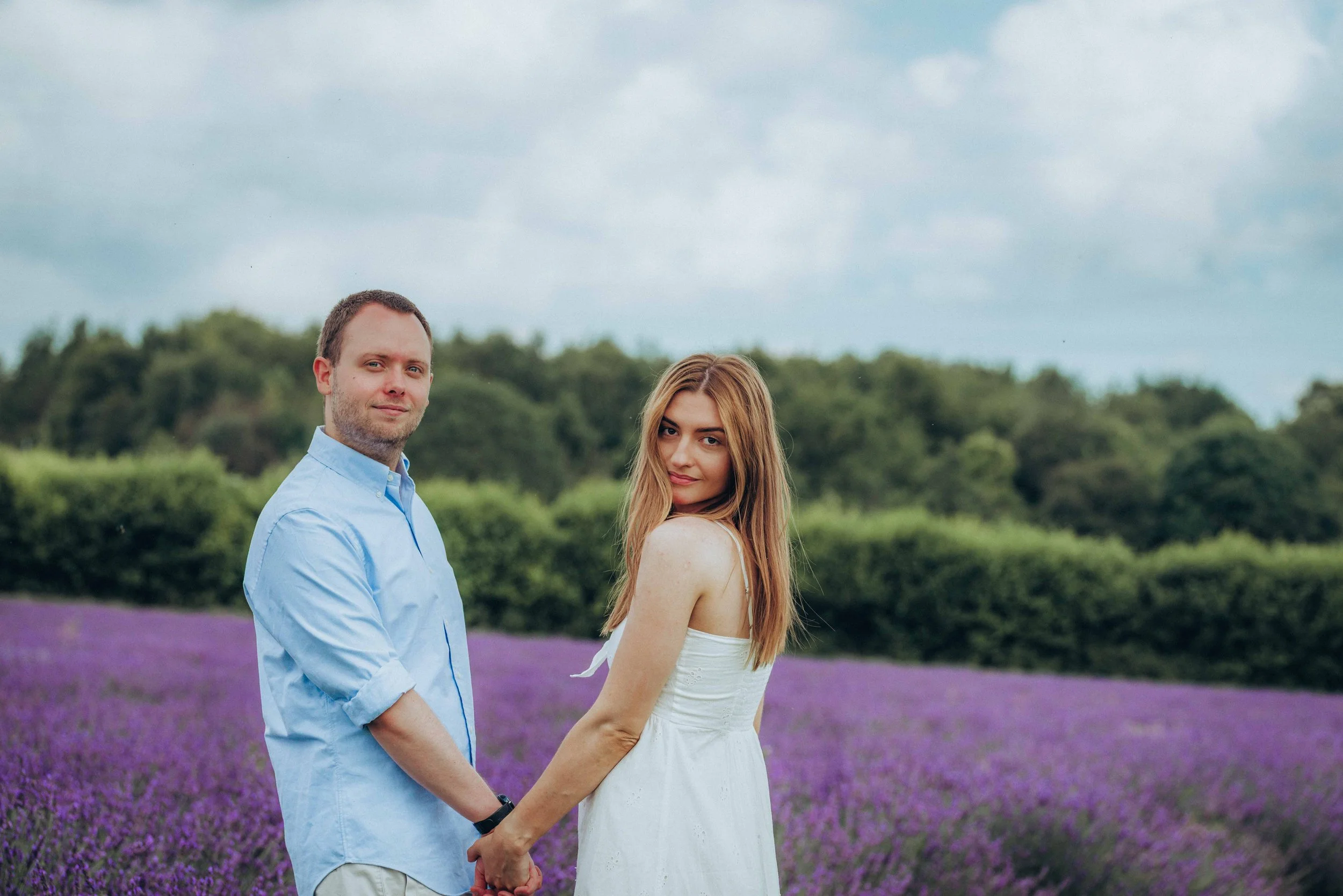Couple holding hands and standing in front of a lavender field at Castle Farm in Kent
