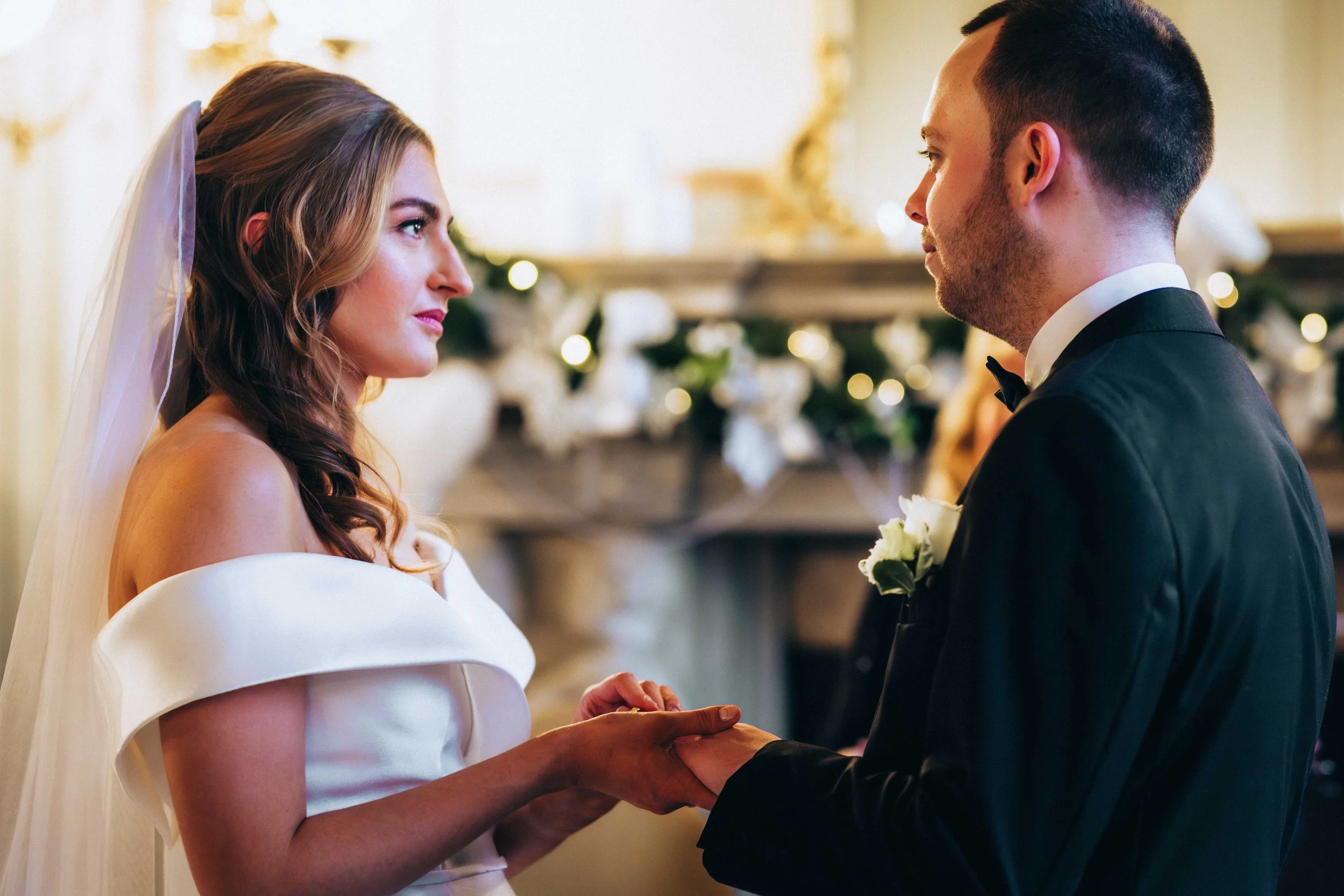 Bride and groom exchanging rings during a christmassy wedding ceremony at Gosfield Hall in Halstead