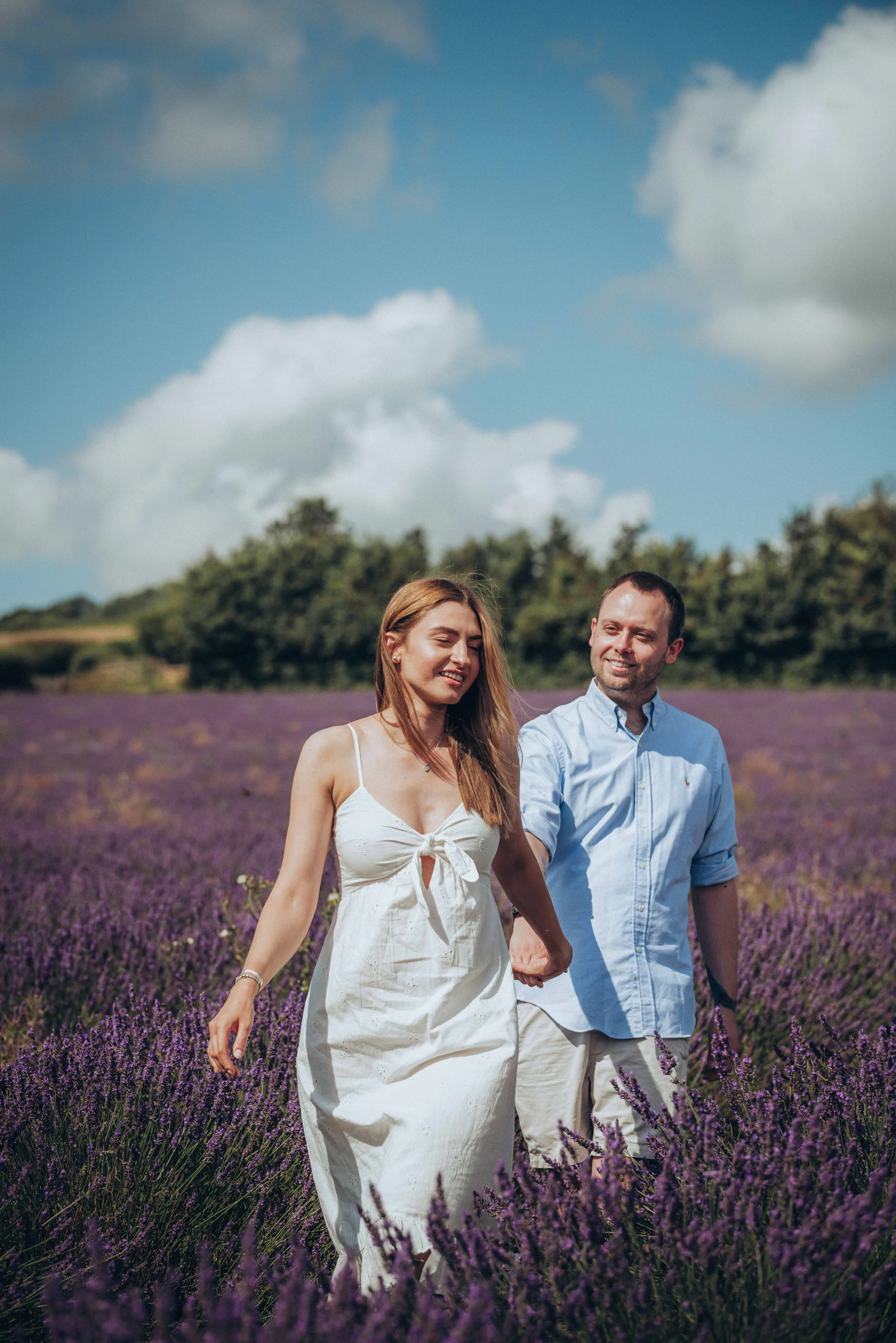 A couple holding hands and walking together through a lavender field at Castle Farm in Kent