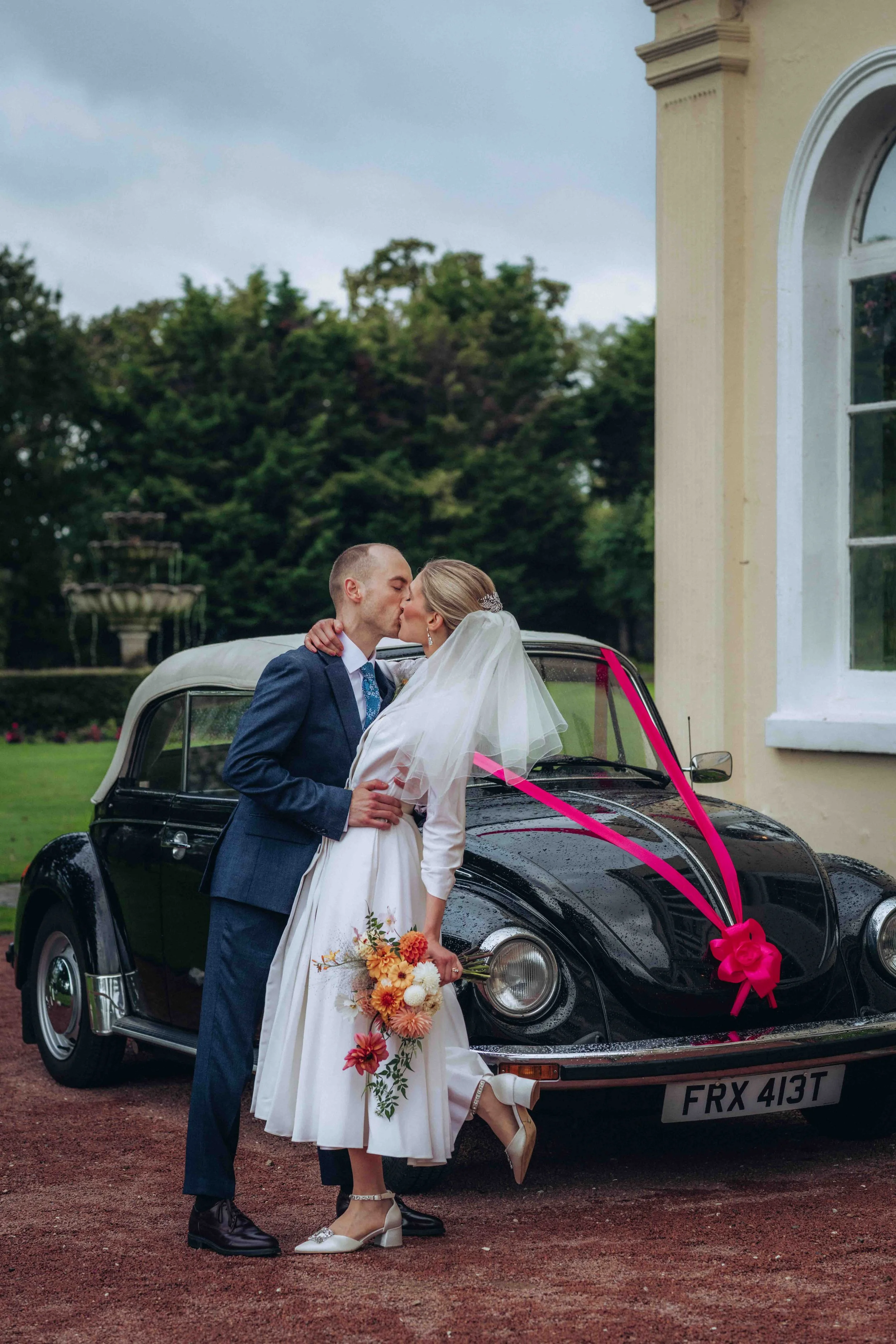 Bride and groom kiss in front of their vintage car at The Lawn in Rochford, Essex wedding photographer