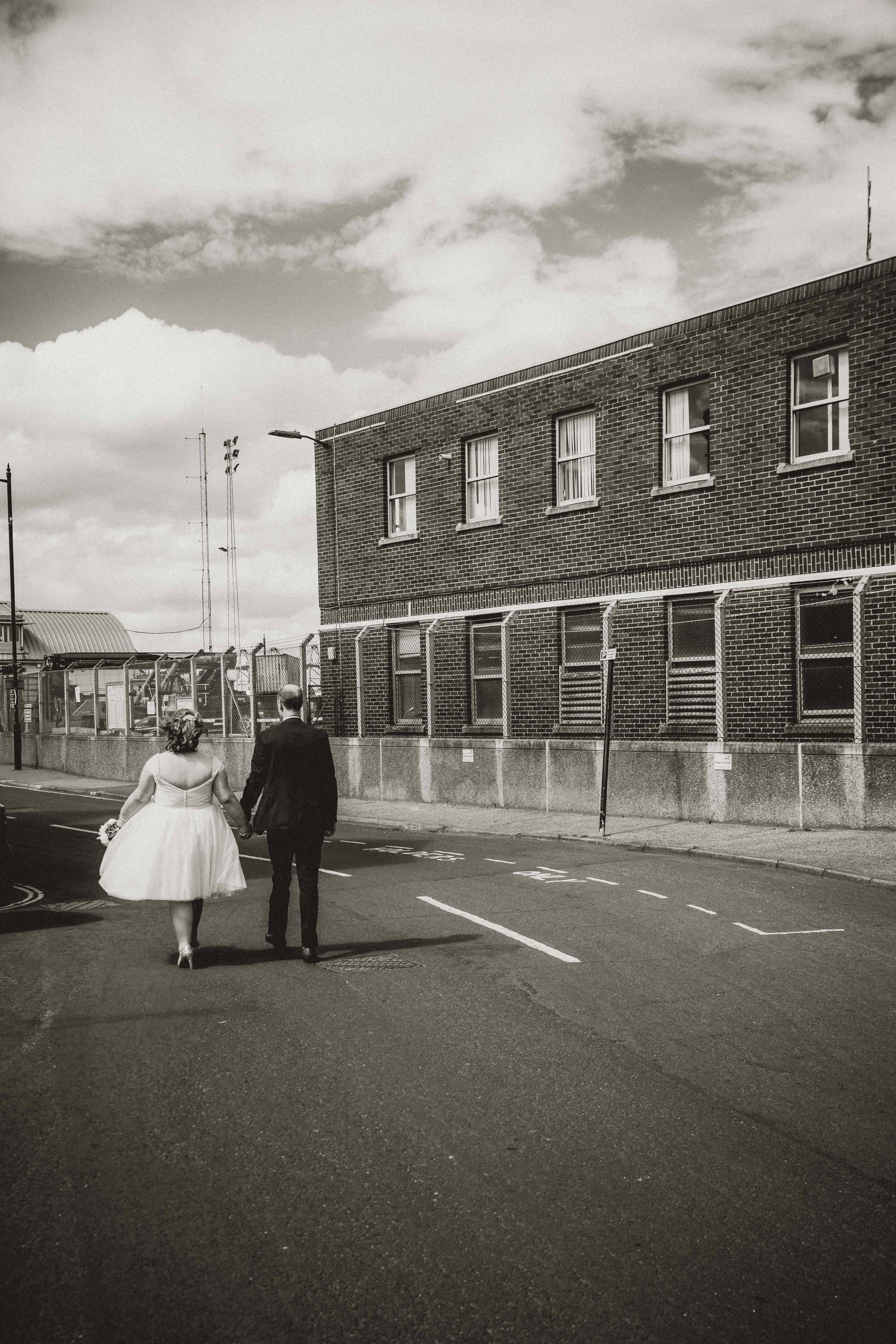 Bride and groom holding hands and walking away in the middle of a road in Harwich in Essex