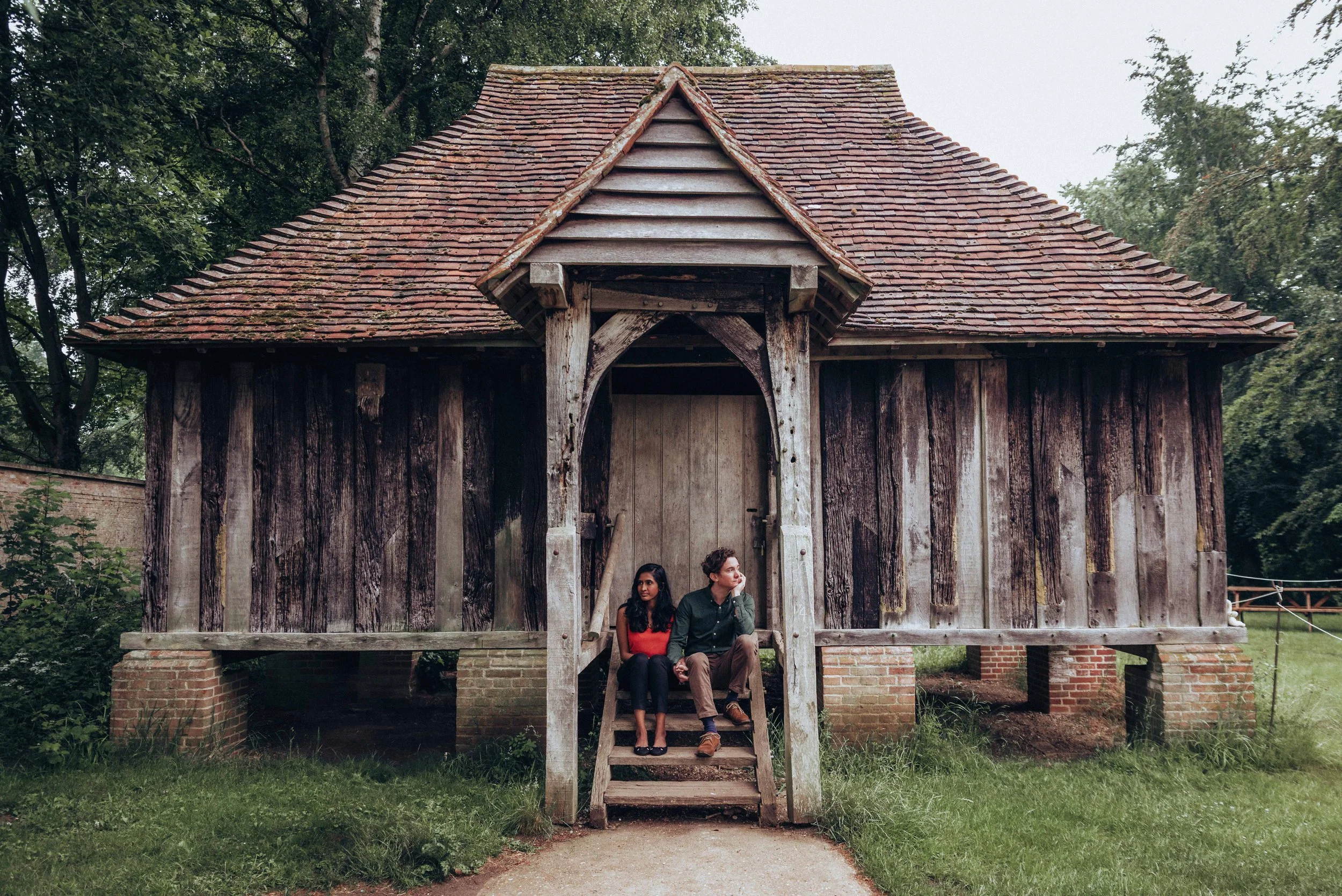 couple sitting on steps of old wooden building for engagement session near Cambridge