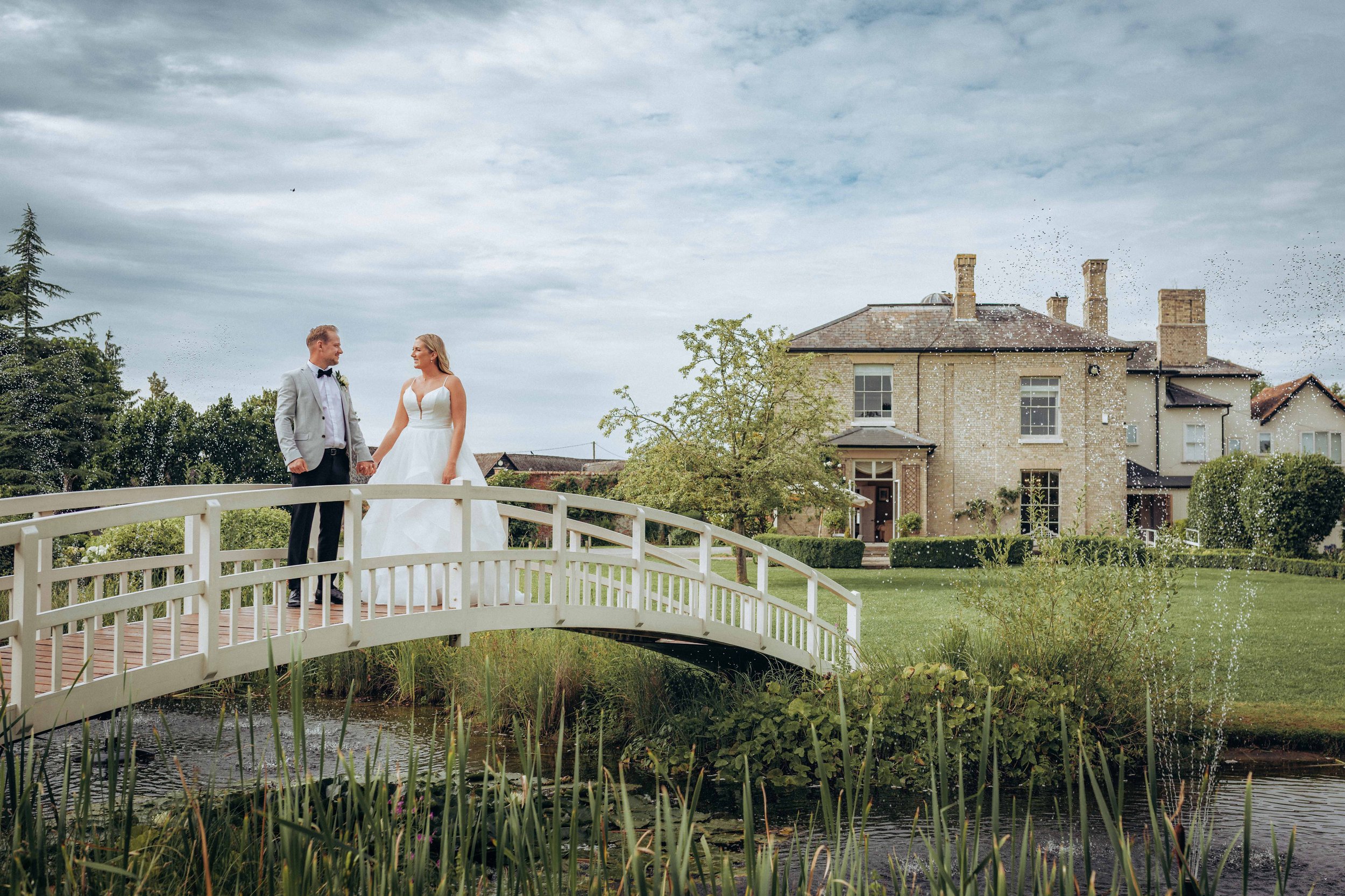 bride and groom sitting in a vintage car after the ceremony and enjoying a glass of champagne together laughing, London wedding photographer