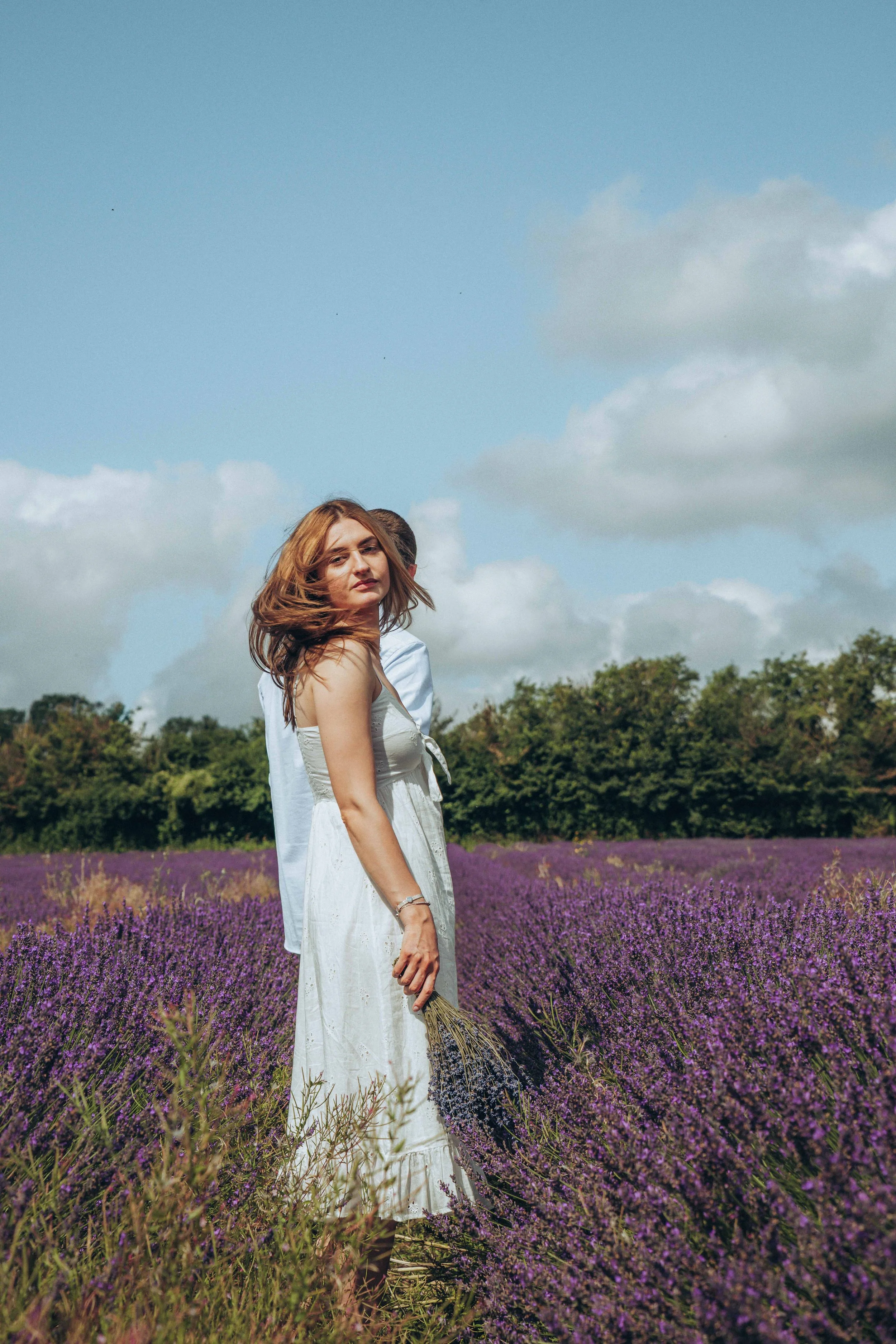 A bride-to-be turning around and facing the camera during a pre-wedding session in a lavender field at Castle Farm in Kent