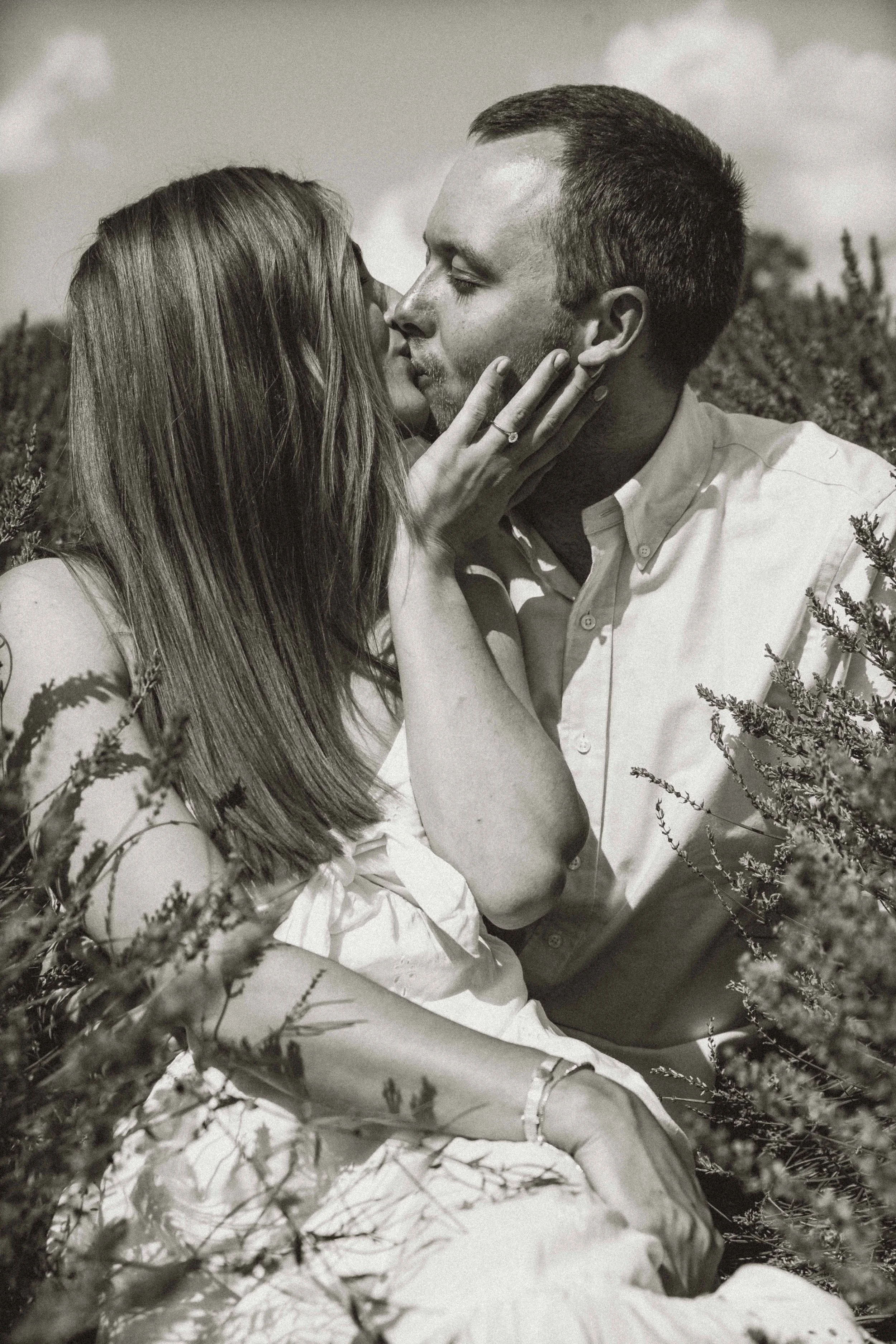A couple sitting down and kissing in a lavender field at Castle Farm in Kent