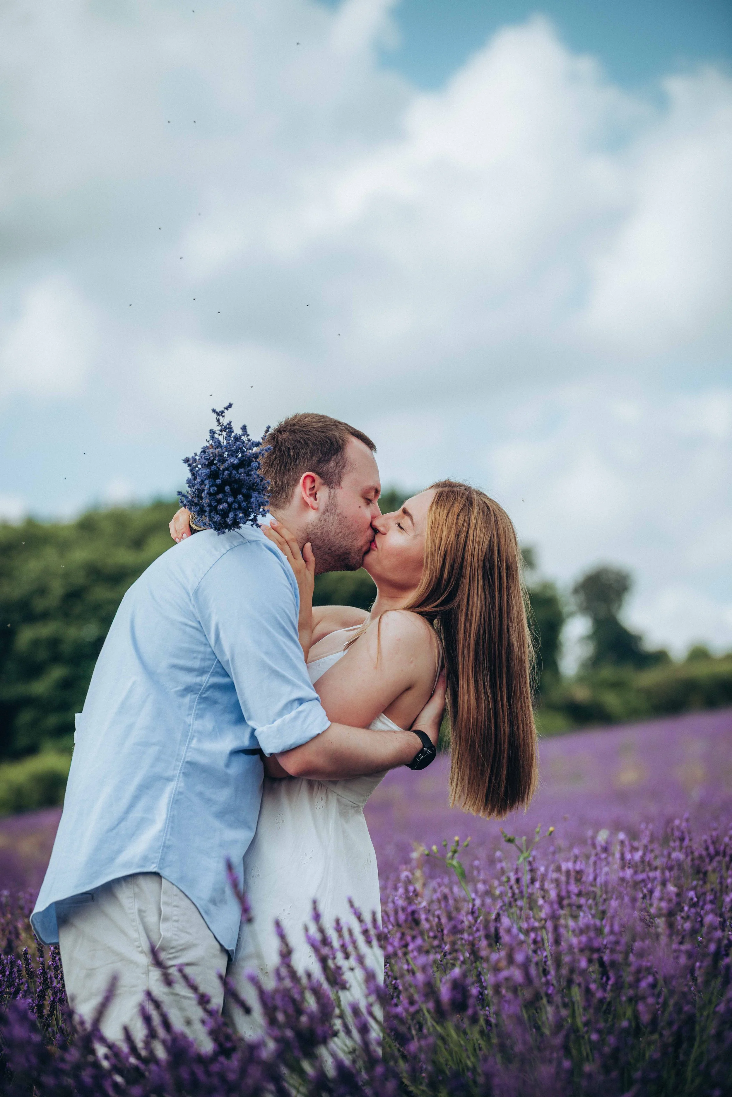 A couple leaning in for a kiss while standing in a lavender field at Castle Farm in Kent