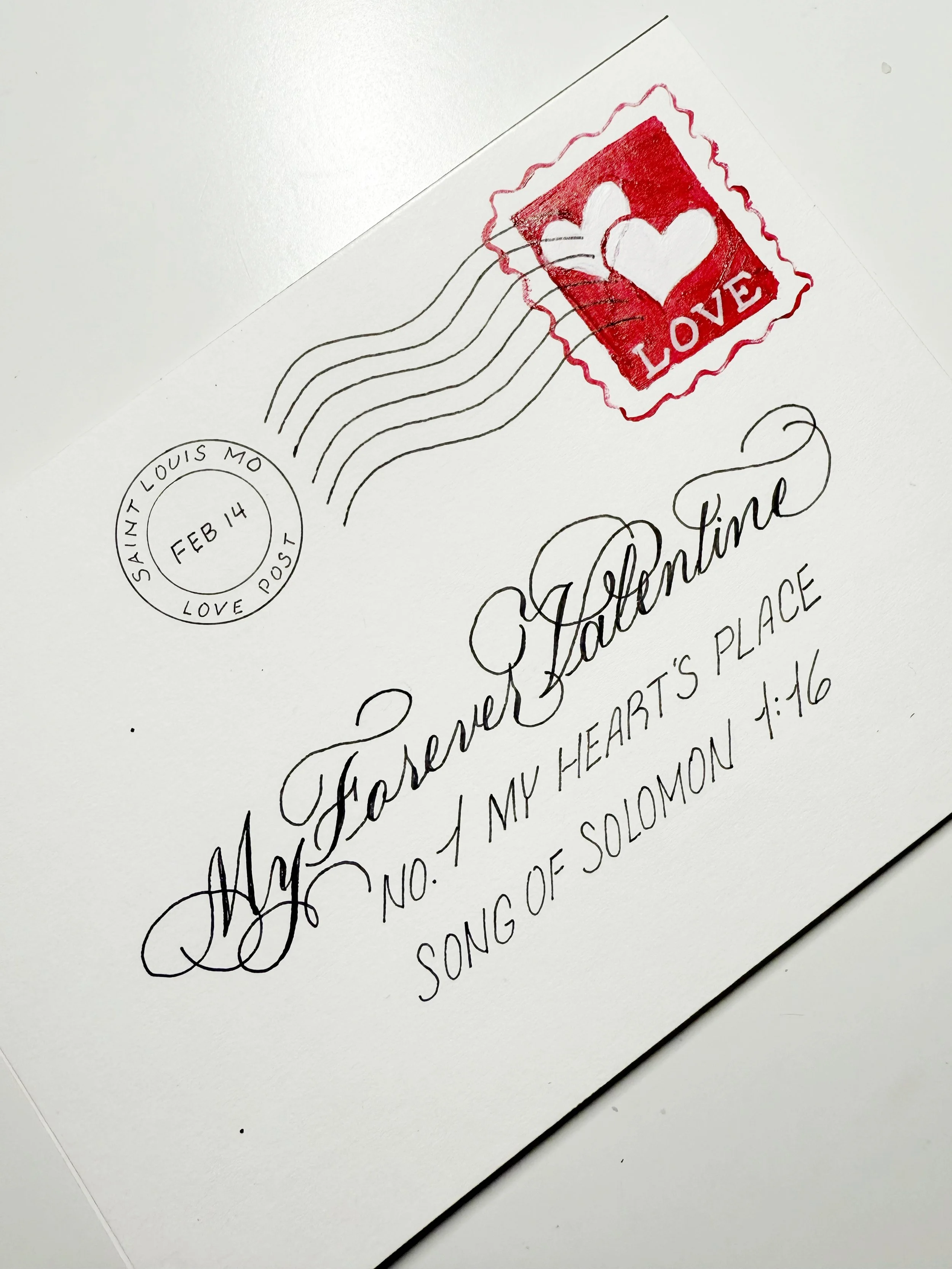 A white envelope with a red stamp featuring a white heart and the word "LOVE," postal markings, and handwritten text that reads "Always Forever Valentine, No. 1 My Heart's Place, Song of Solomon 1:16."