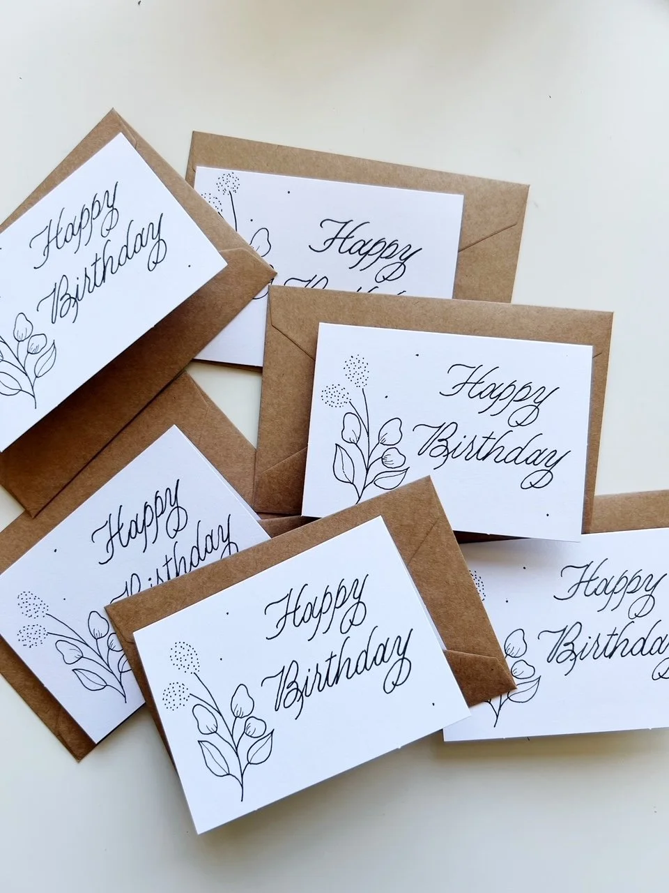 Folded enclosure cards with happy birthday in calligraphy and small floral sketch