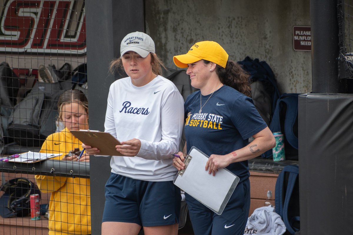 Former SIU athletes, Madi Eberle (Murray State softball assistant coach) and Elizabeth Warwick (Murray State softball graduate assistant), discuss strategy during a game Apr. 26, 2025 at Charlotte West Stadium in Carbondale, Illinois. (Jason Isele/Th