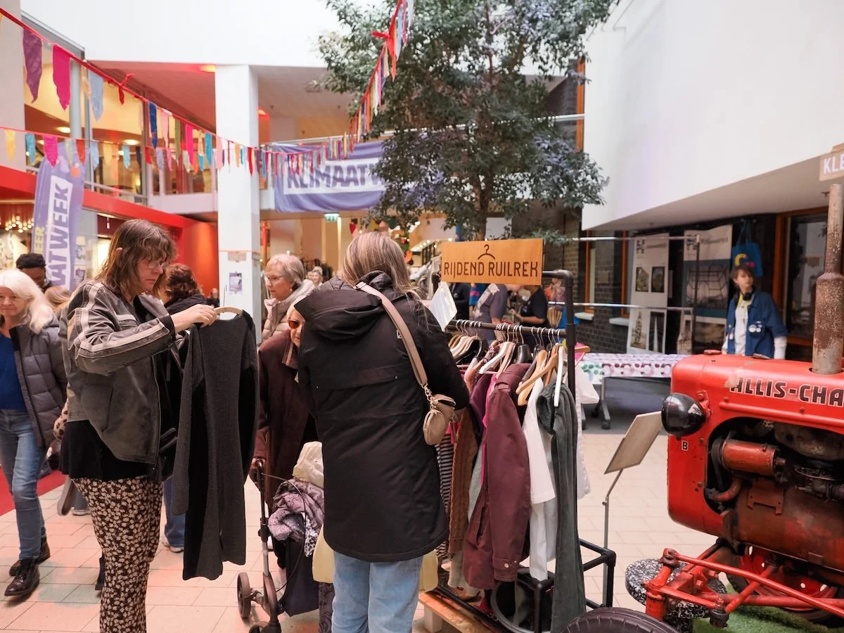 Twee vrouwen zoeken kleding uit bij een ruilrek