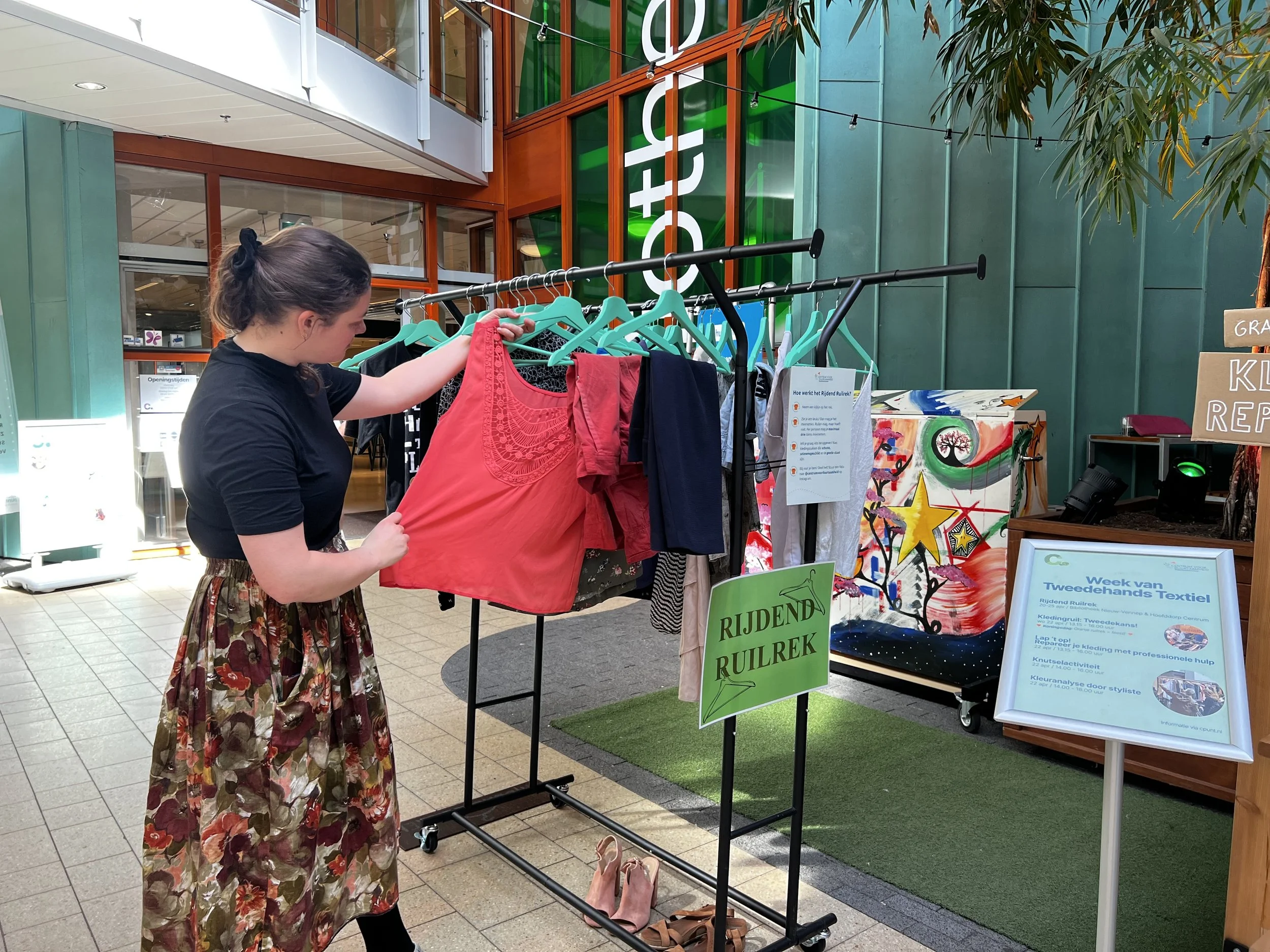 Vrouw bekijkt kledingstuk aan kledingrek Rijdend Ruilrek in Cpunt