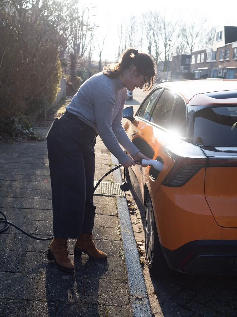 Vrouw zet elektrische auto aan de lader
