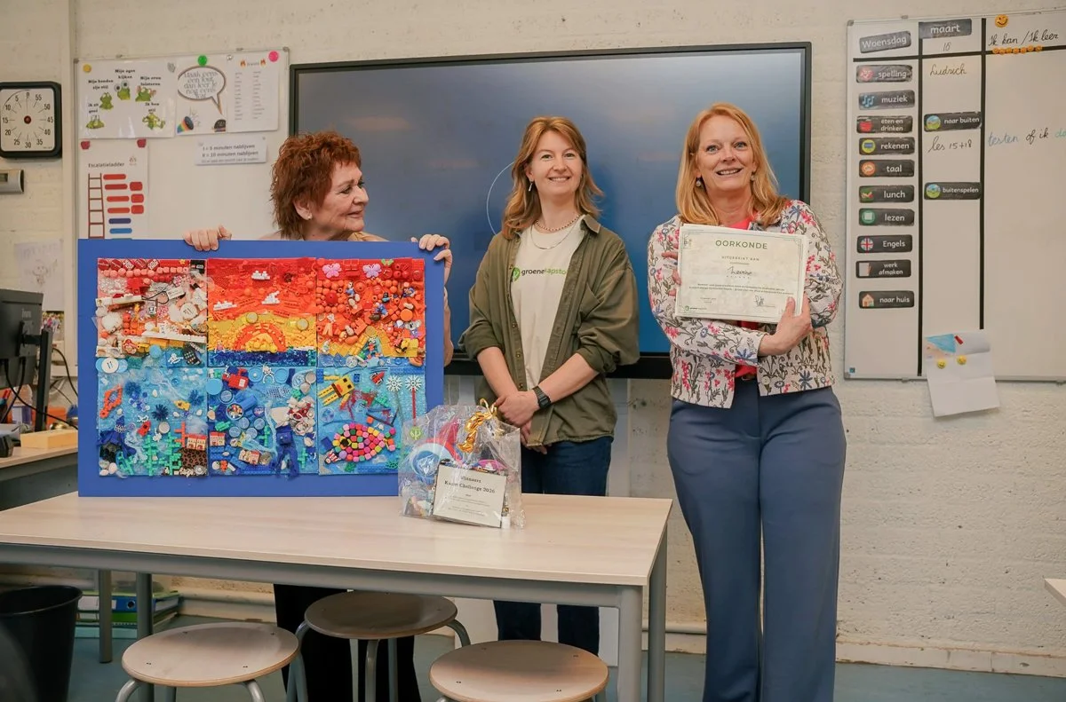De wethouder en twee juffen bij het kunstwerk van een klas