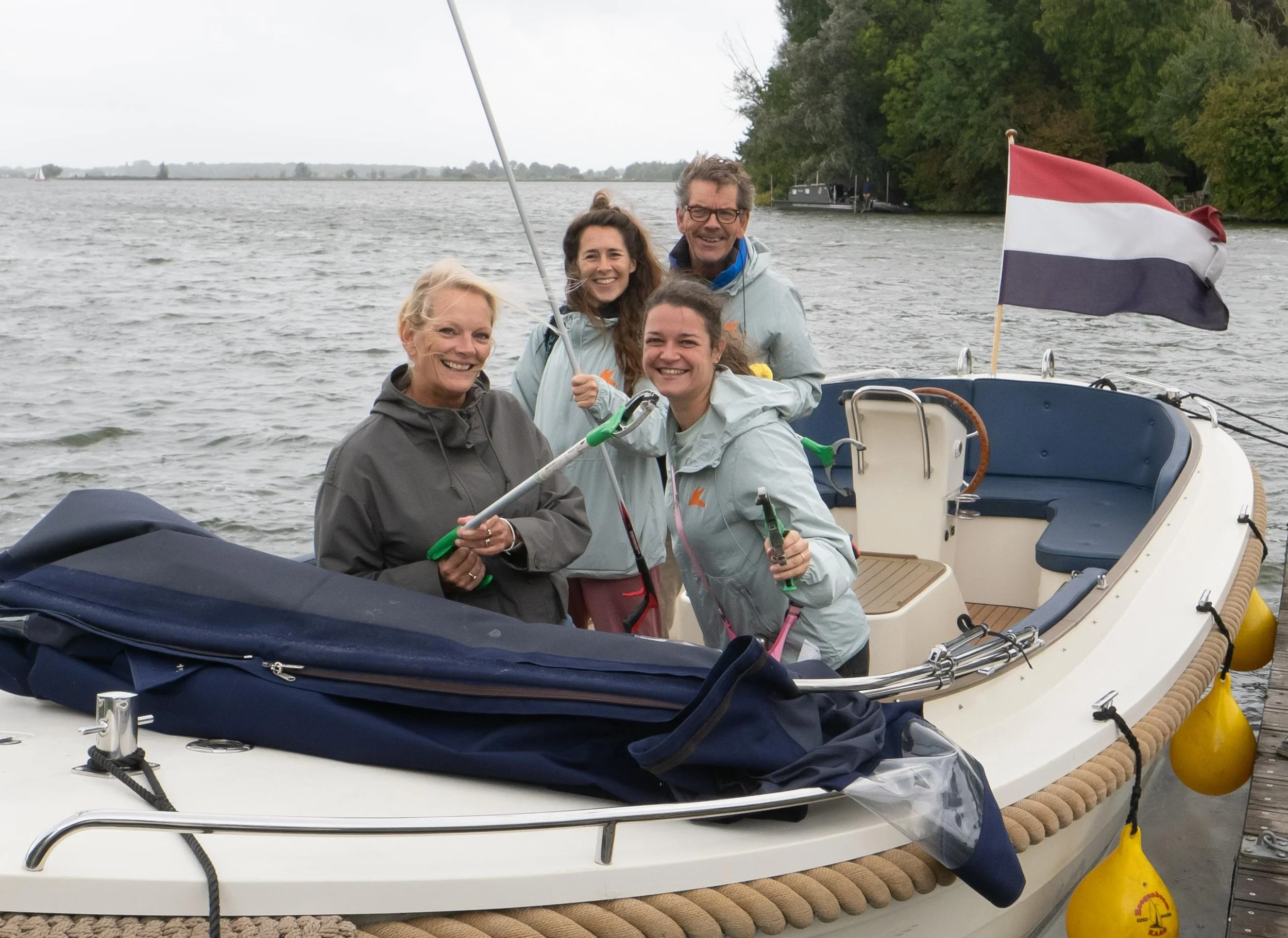 Mensen in bootje op het water met afvalgrijpers