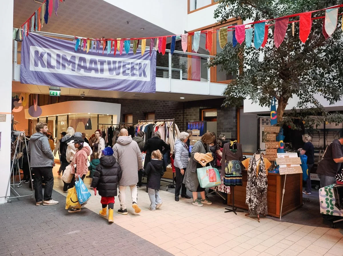 Spandoek van de klimaatweek hangt over een drukke kledingruil bij cpunt