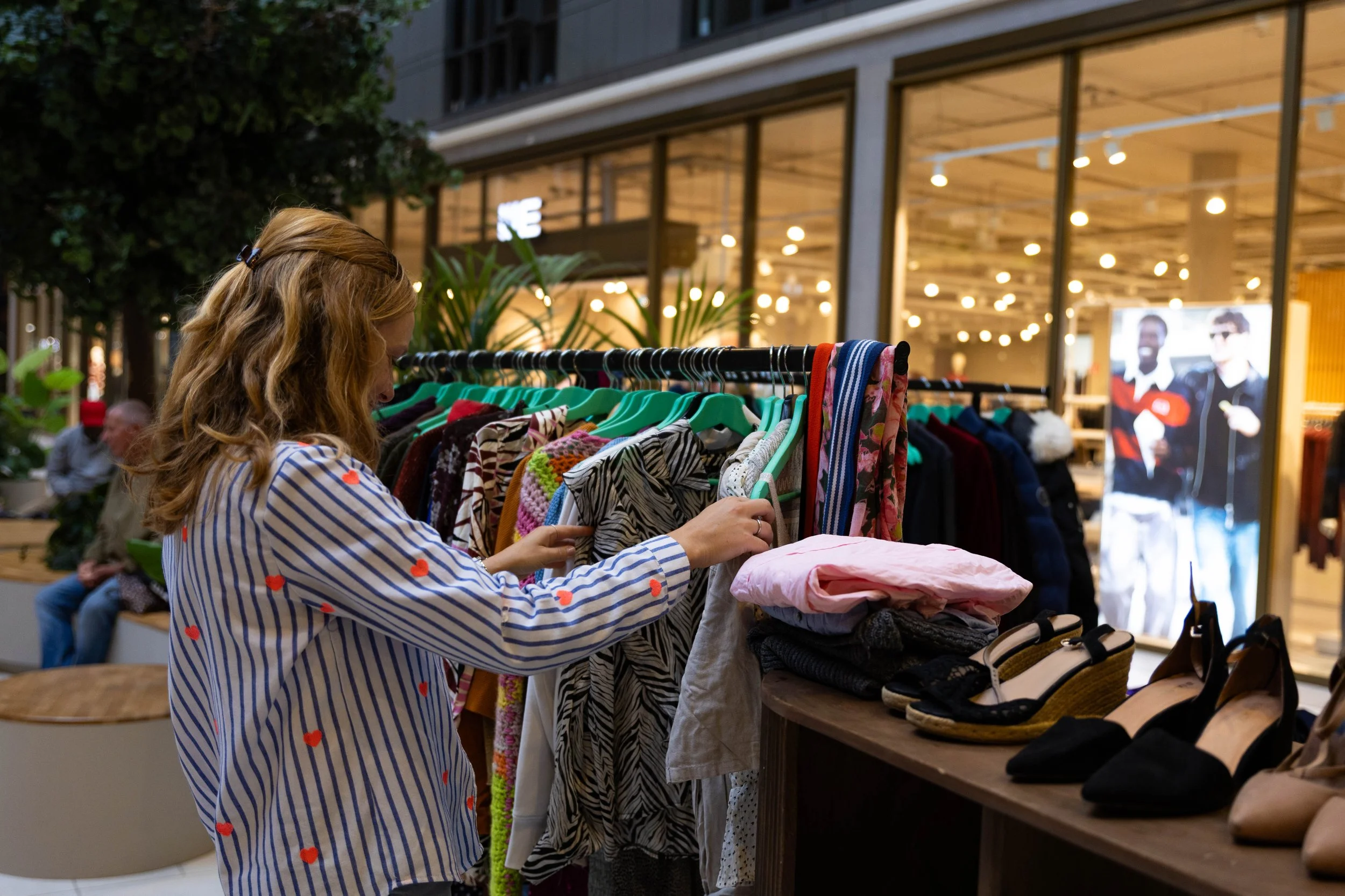 Vrouw bekijkt kleding aan kledingrek