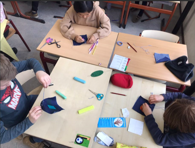 Drie kinderen knutselen met textiel aan tafel