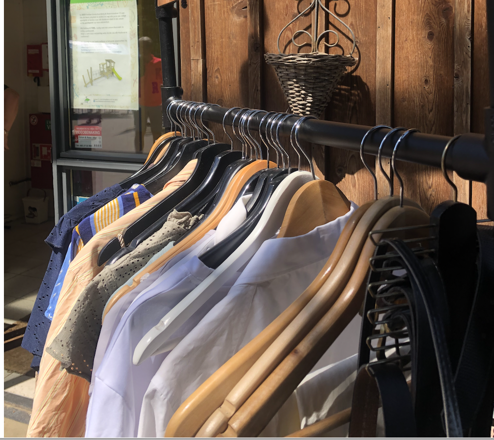 Kledingrek met kledinghangers waar diverse kledingstukken aan hangen