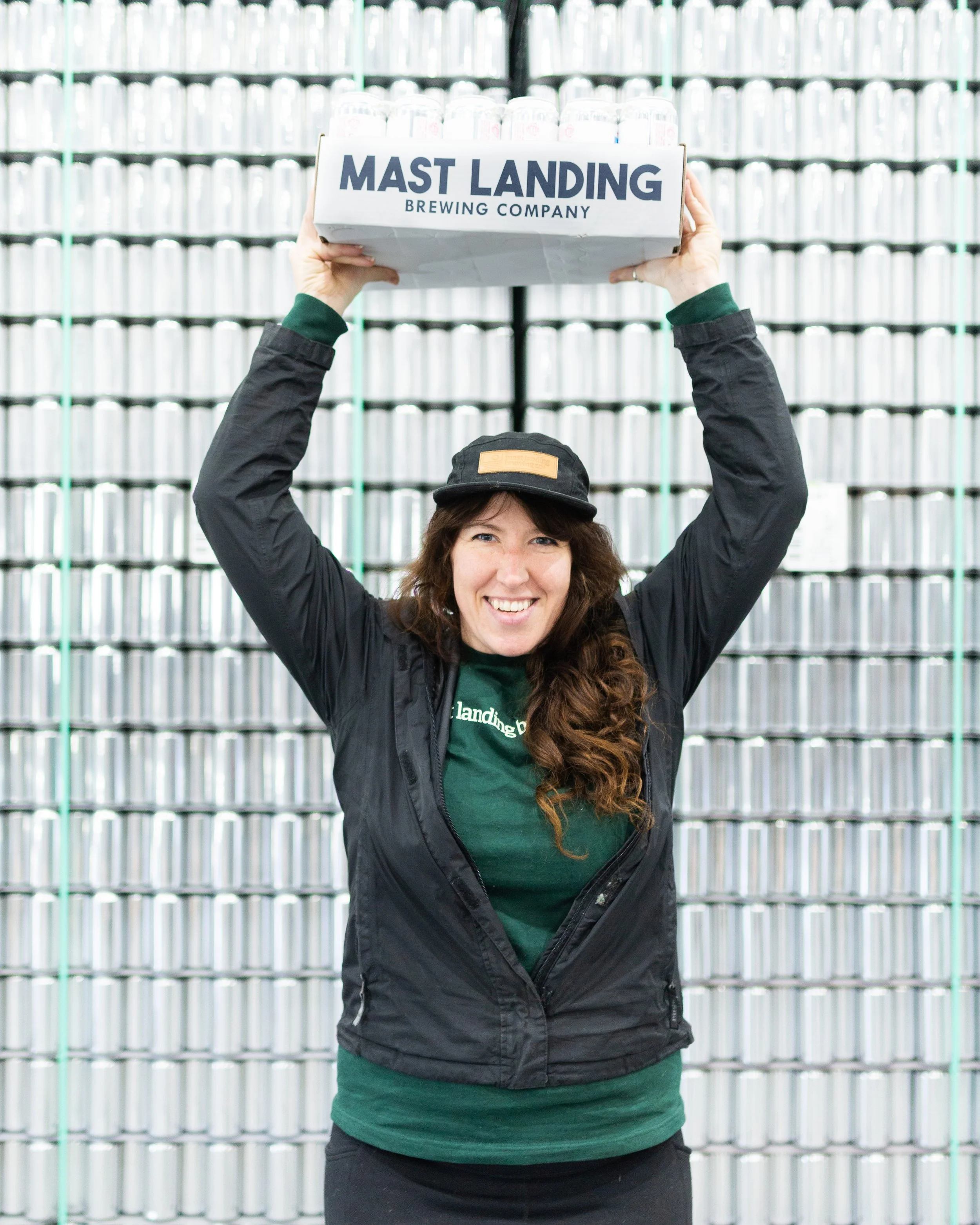 mast landing employee holds case of beer over her head